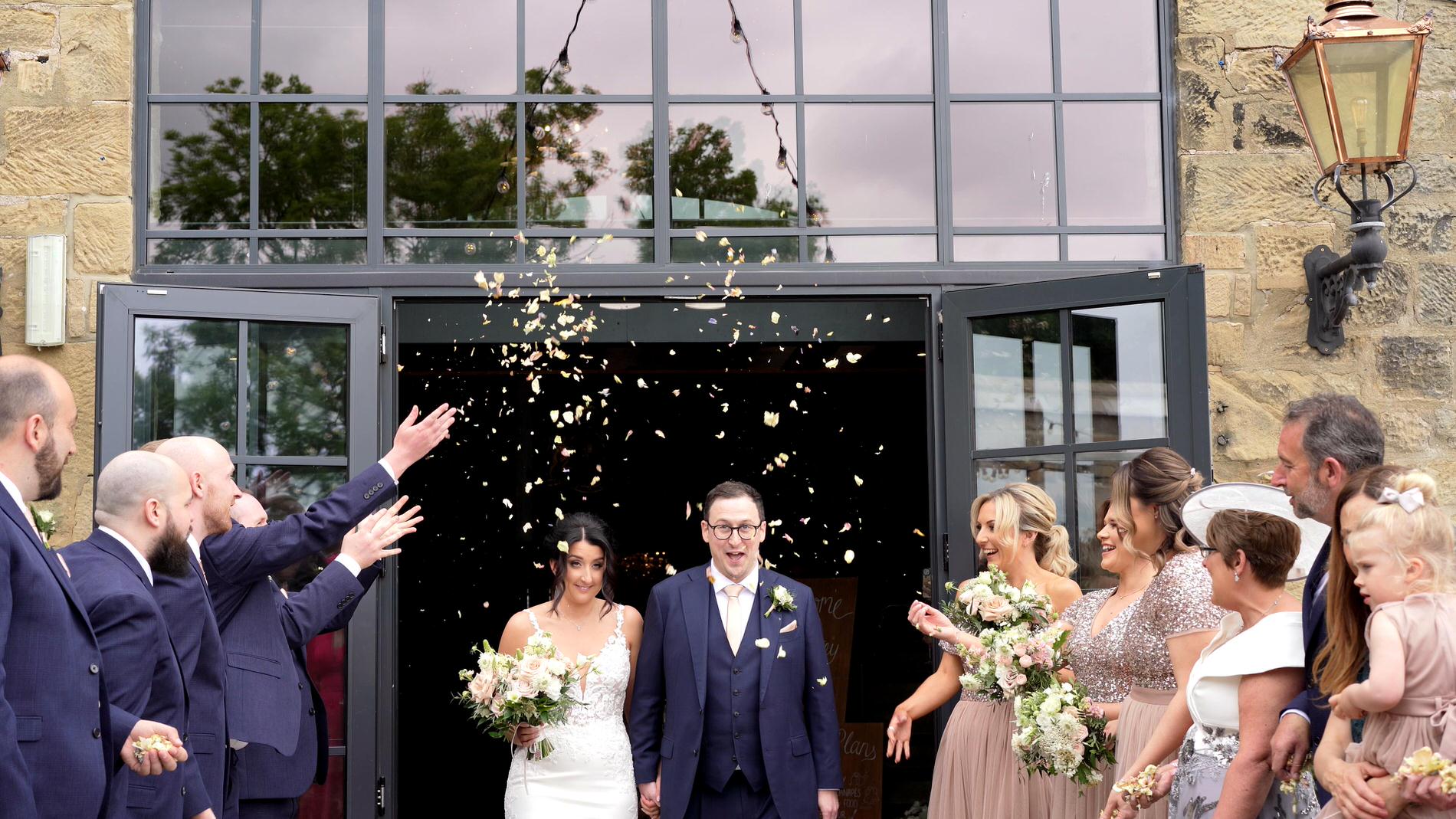 a video still of a couple walking out to confetti outside Wharfdale Grange