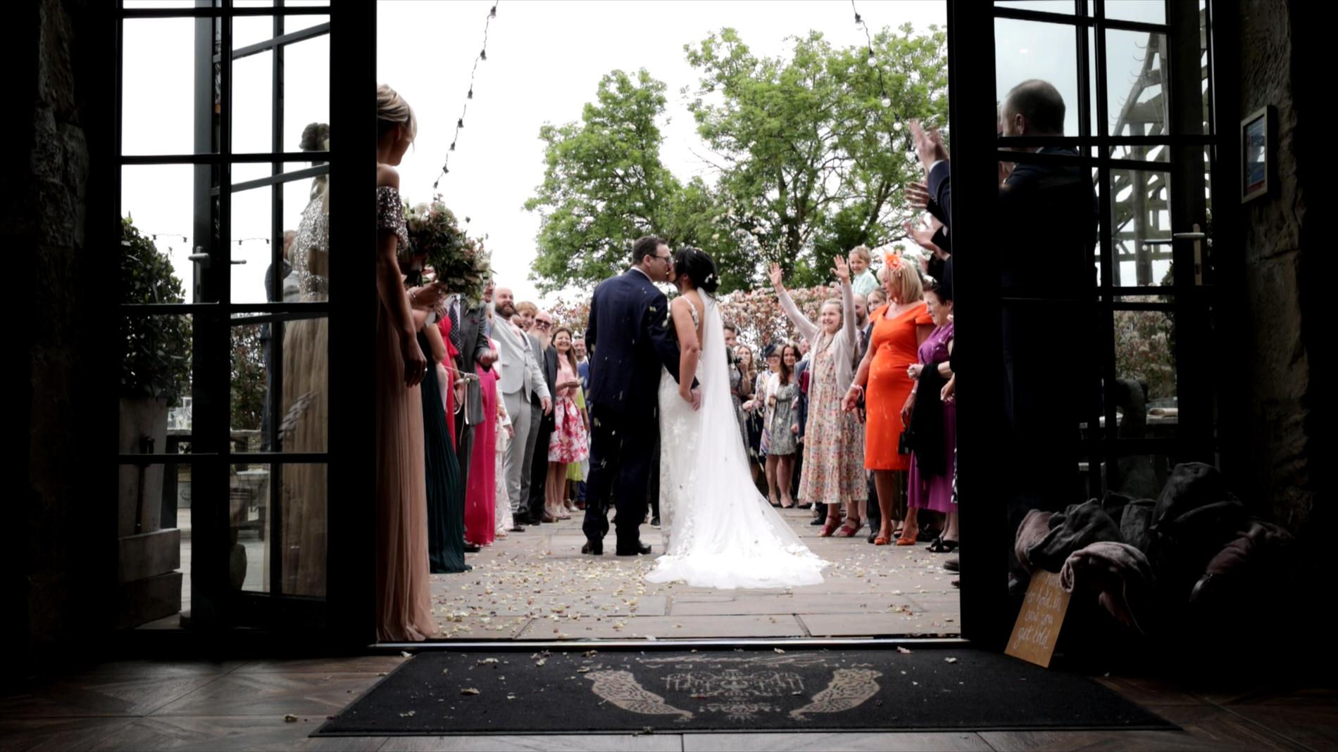a couple kiss whilst being showered in confetti