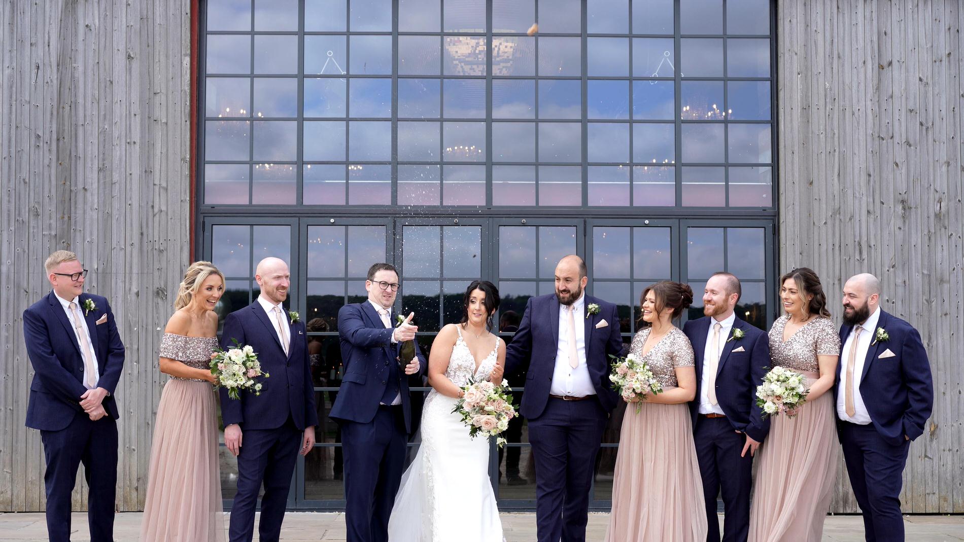 the groom tries to spray prosecco during wedding photos at Wharfdale Grange