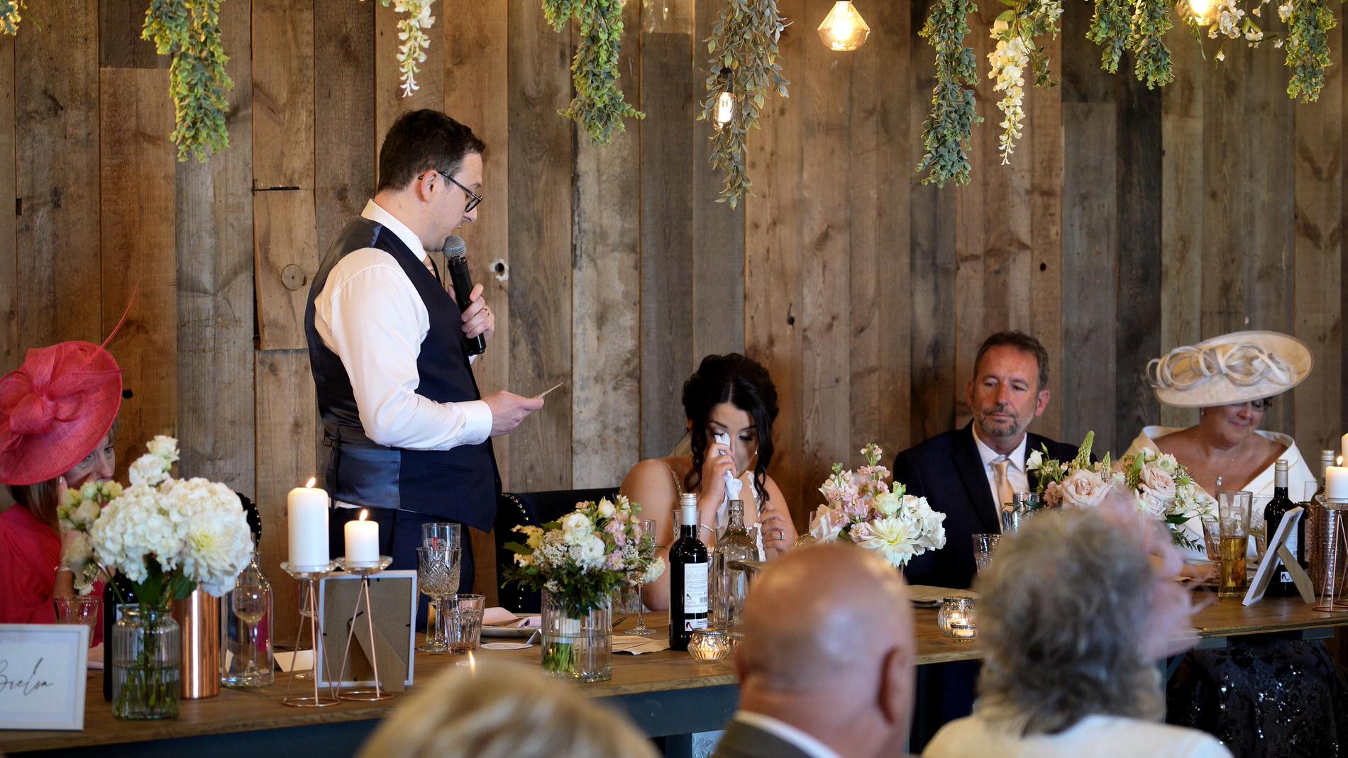 bride wipes away tears during grooms speech