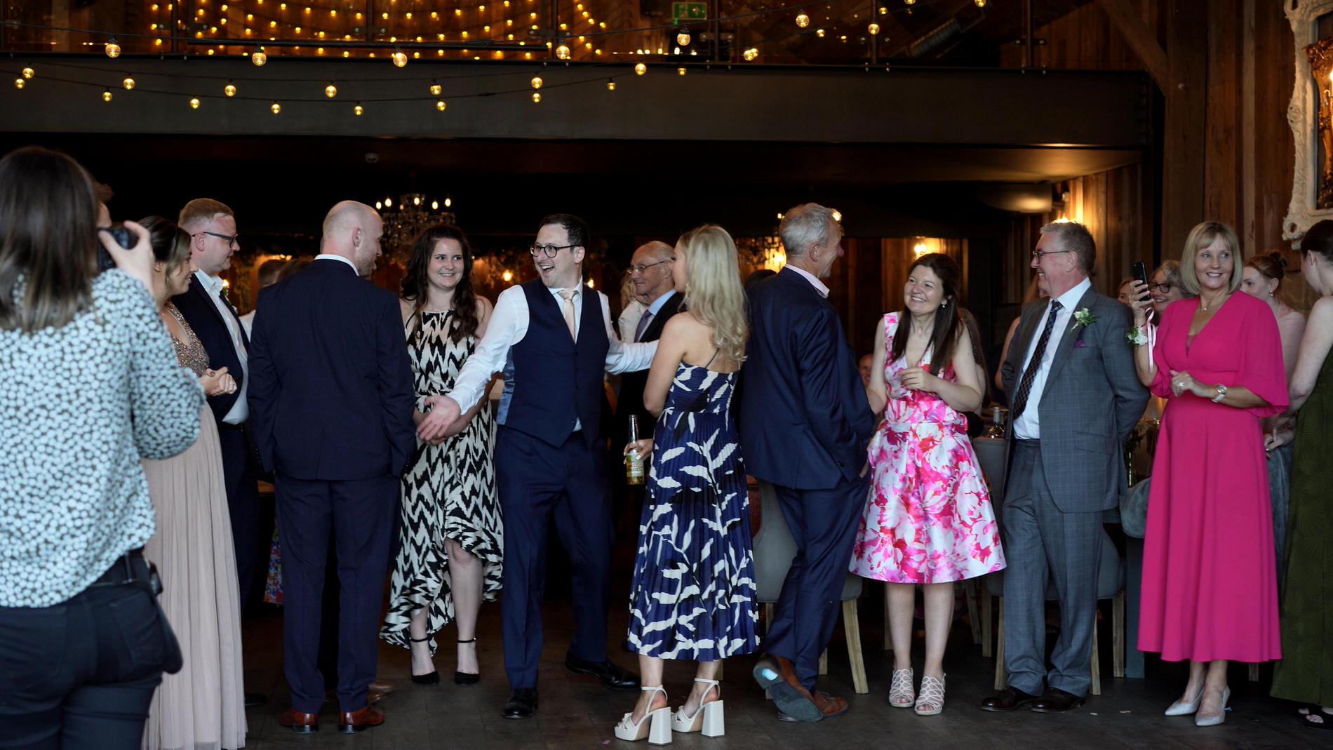 guests laugh as the groom turns up late for the cake cutting