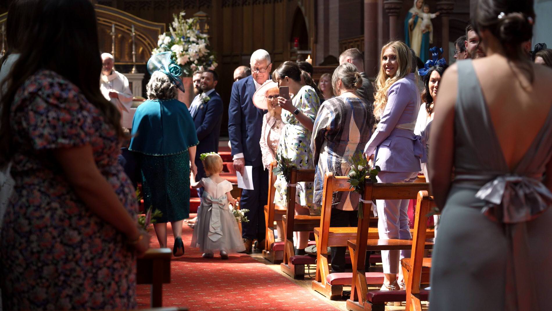 Mum and flower girl walk down the church aisle