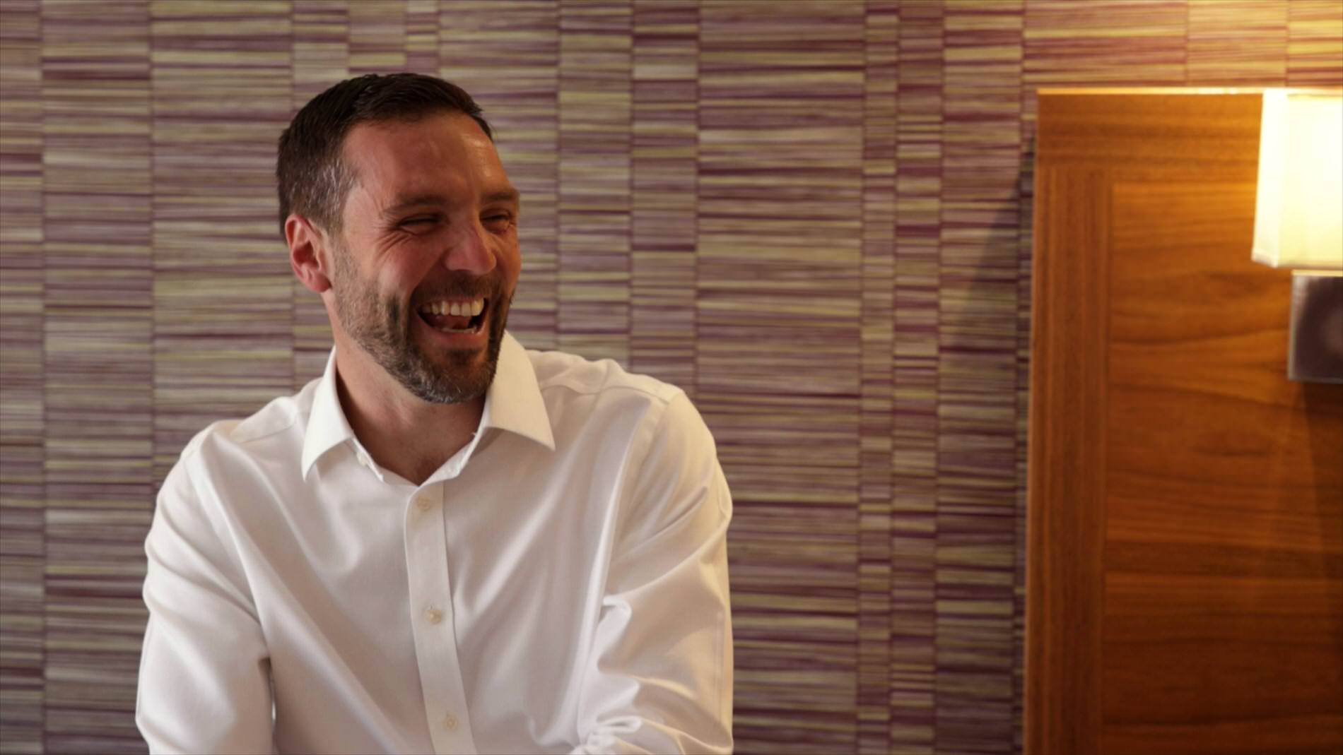 groom laughs whilst sat in Chester apartment