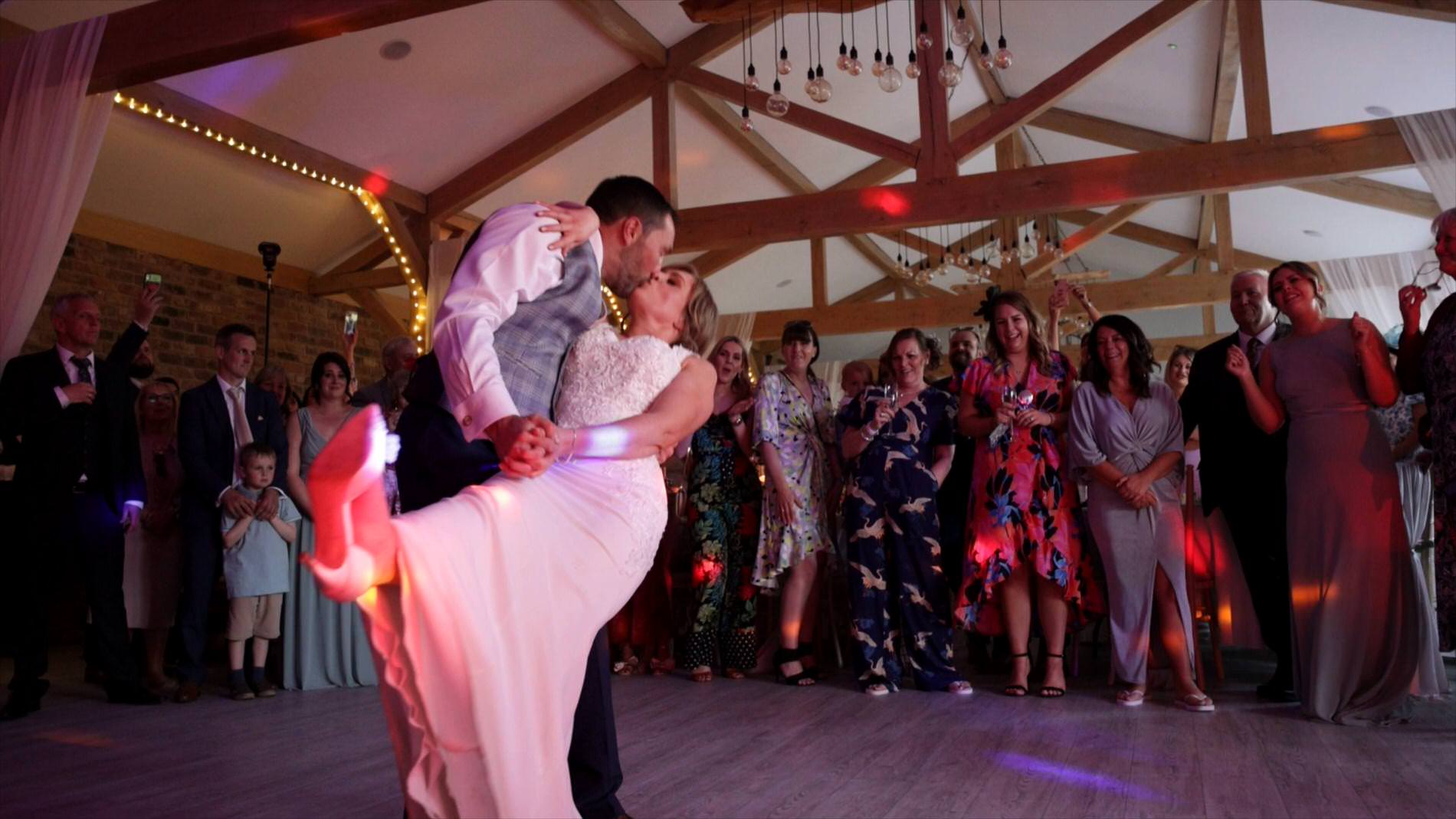 the groom dips the bride for a cheer during their first dance