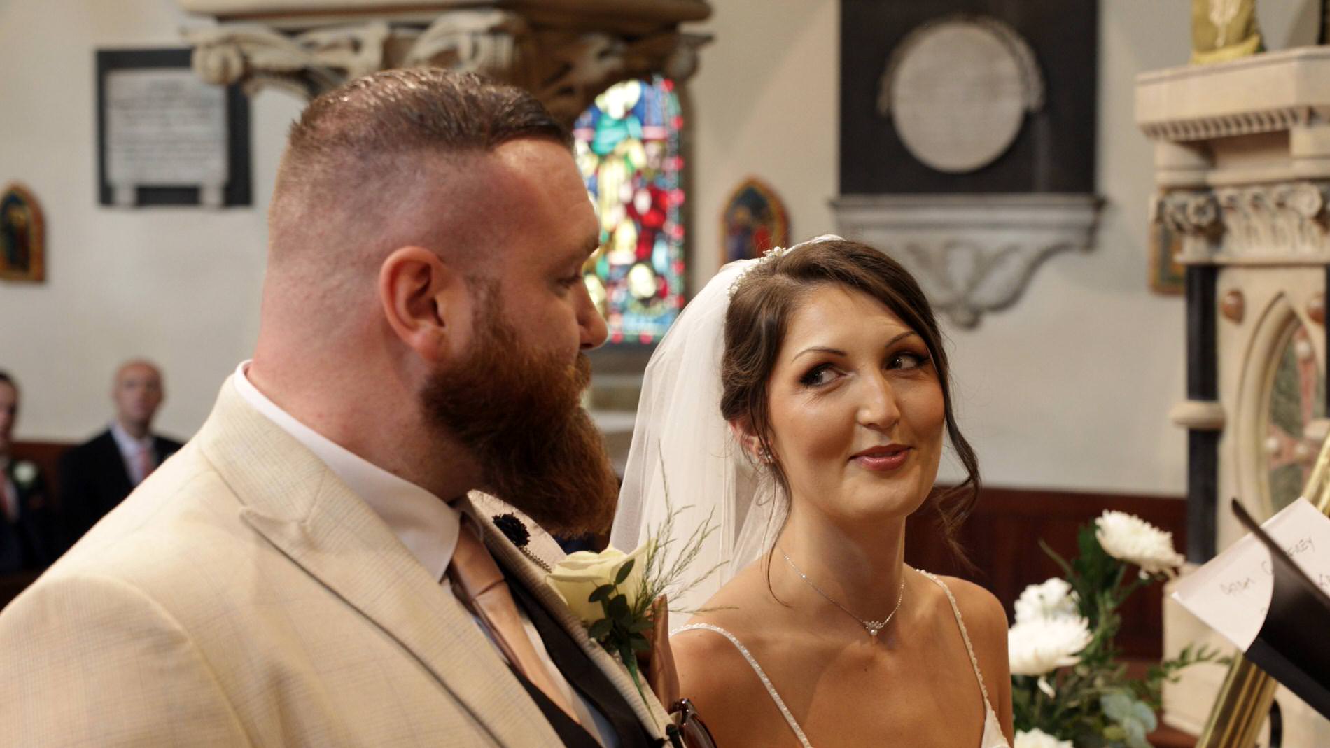 a bride smiles at her groom during the church ceremony