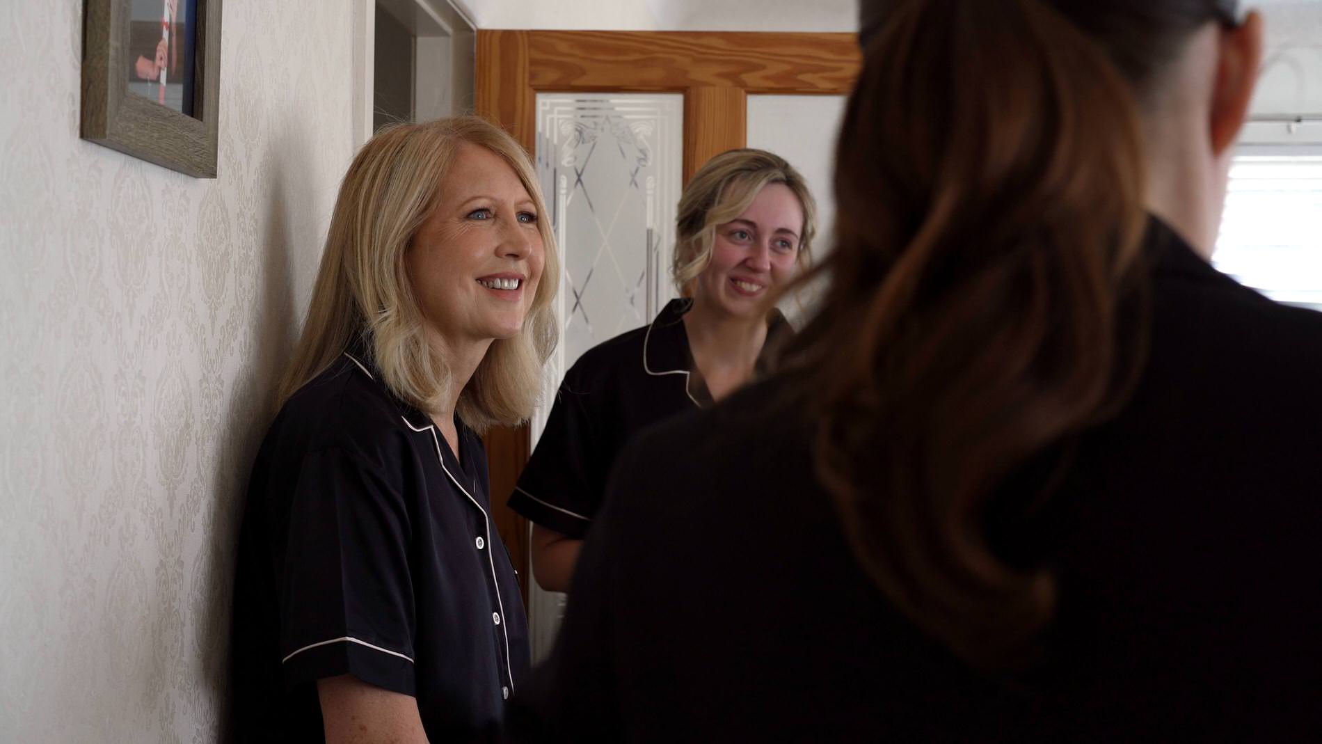 mother of the bride smiles at her daughter getting her makeup done