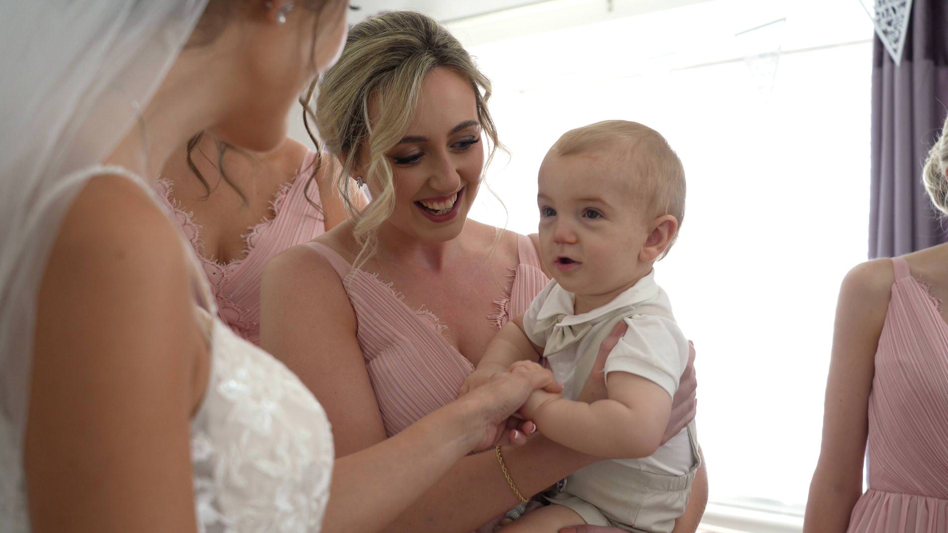 a bridesmaid holds the brides son