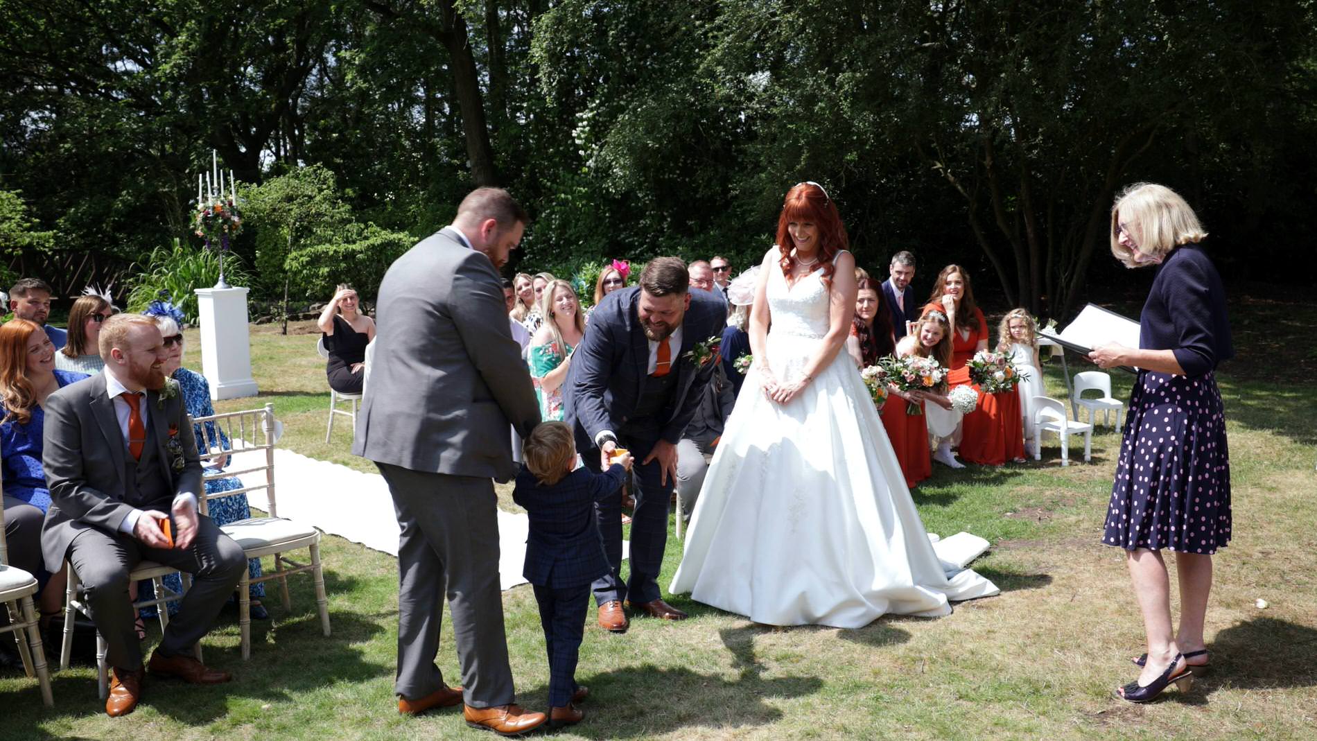 page boy gives the wedding rings to his dad during the wedding ceremony