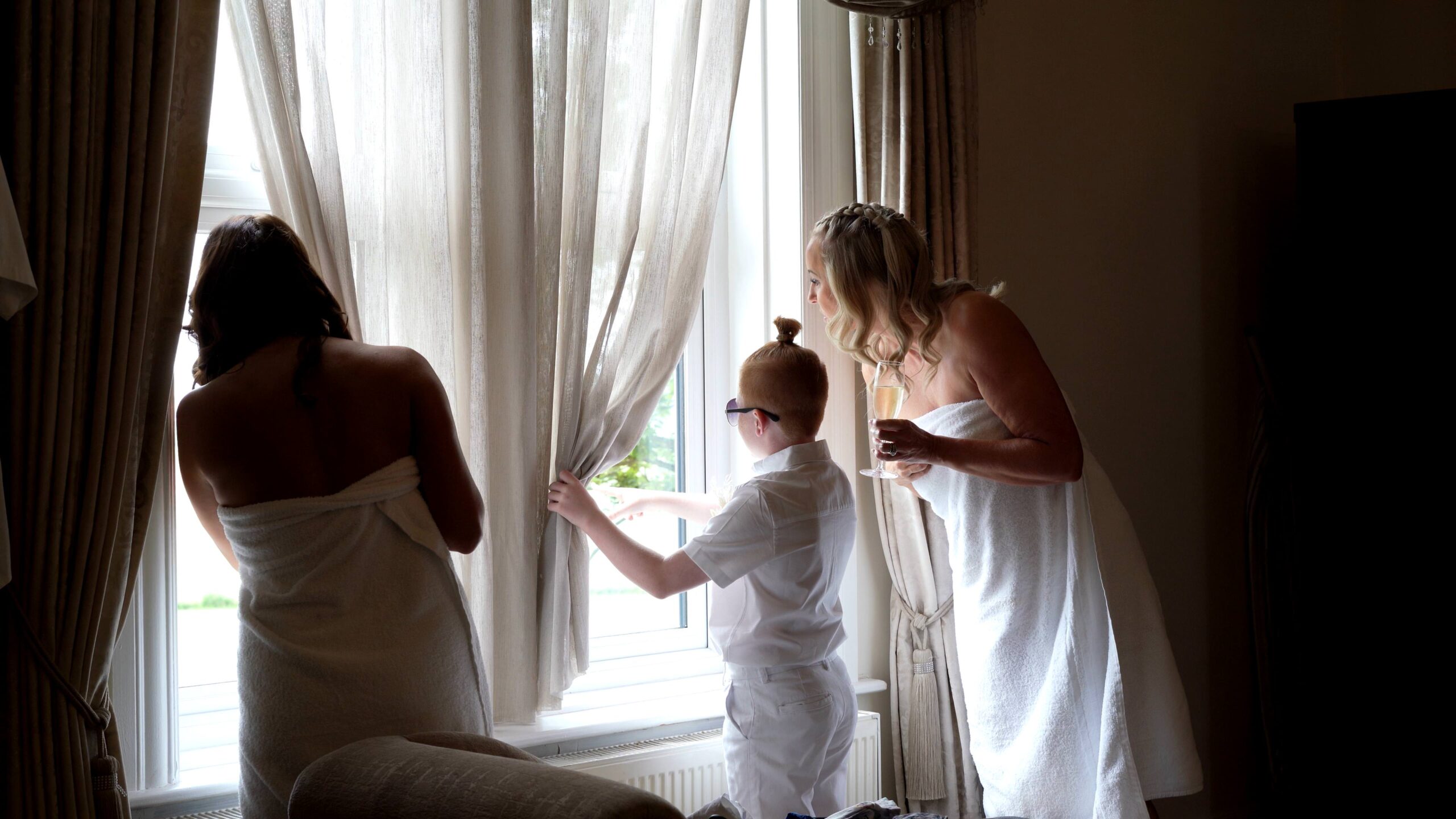 a bride and her bridal party look out of the bridal suite window
