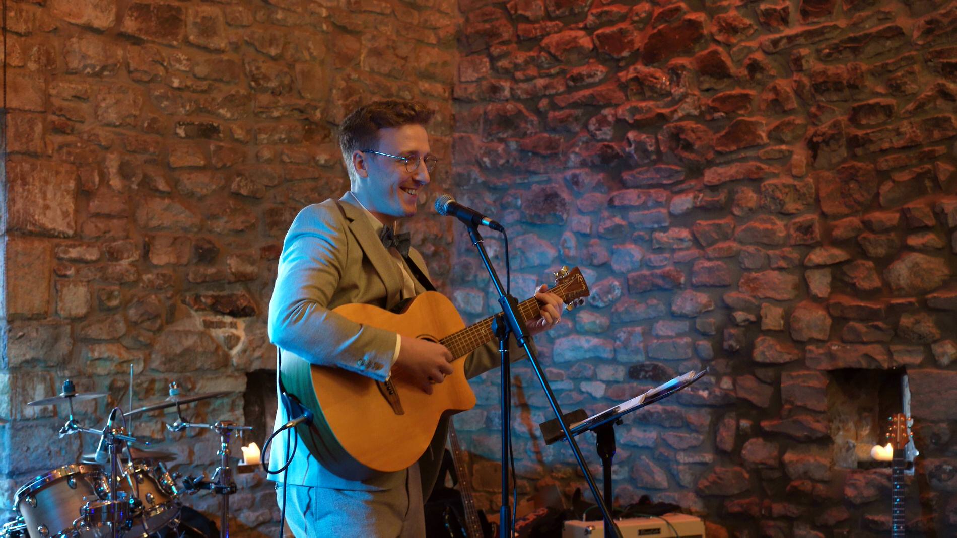 a wedding guests sings for the couple at their wedding with a guitar