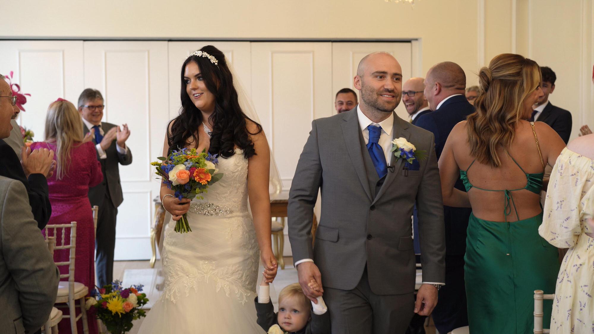 a couple walk out of the ceremony room smiling