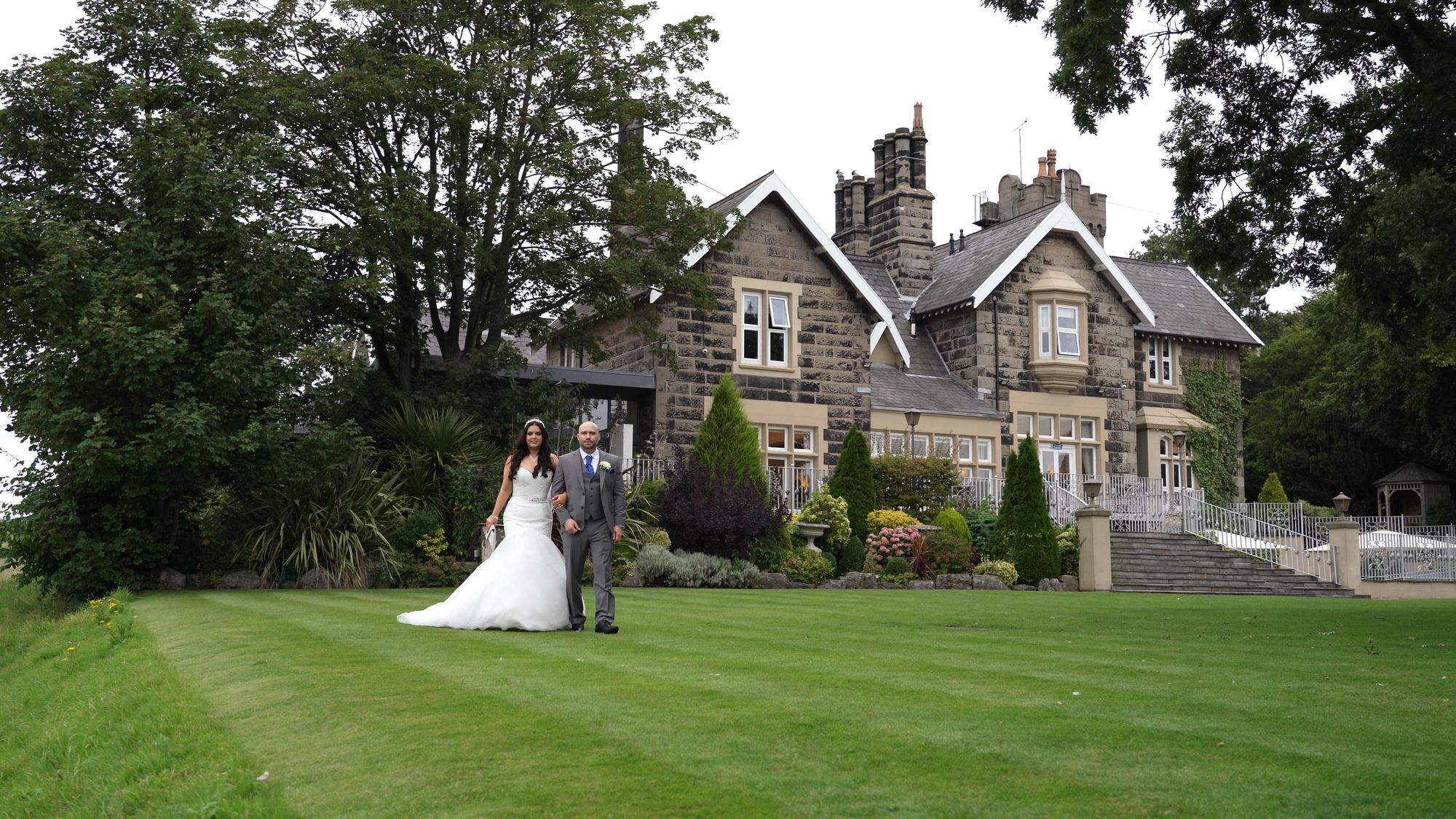 a bride and groom walk along the gardens at West Tower