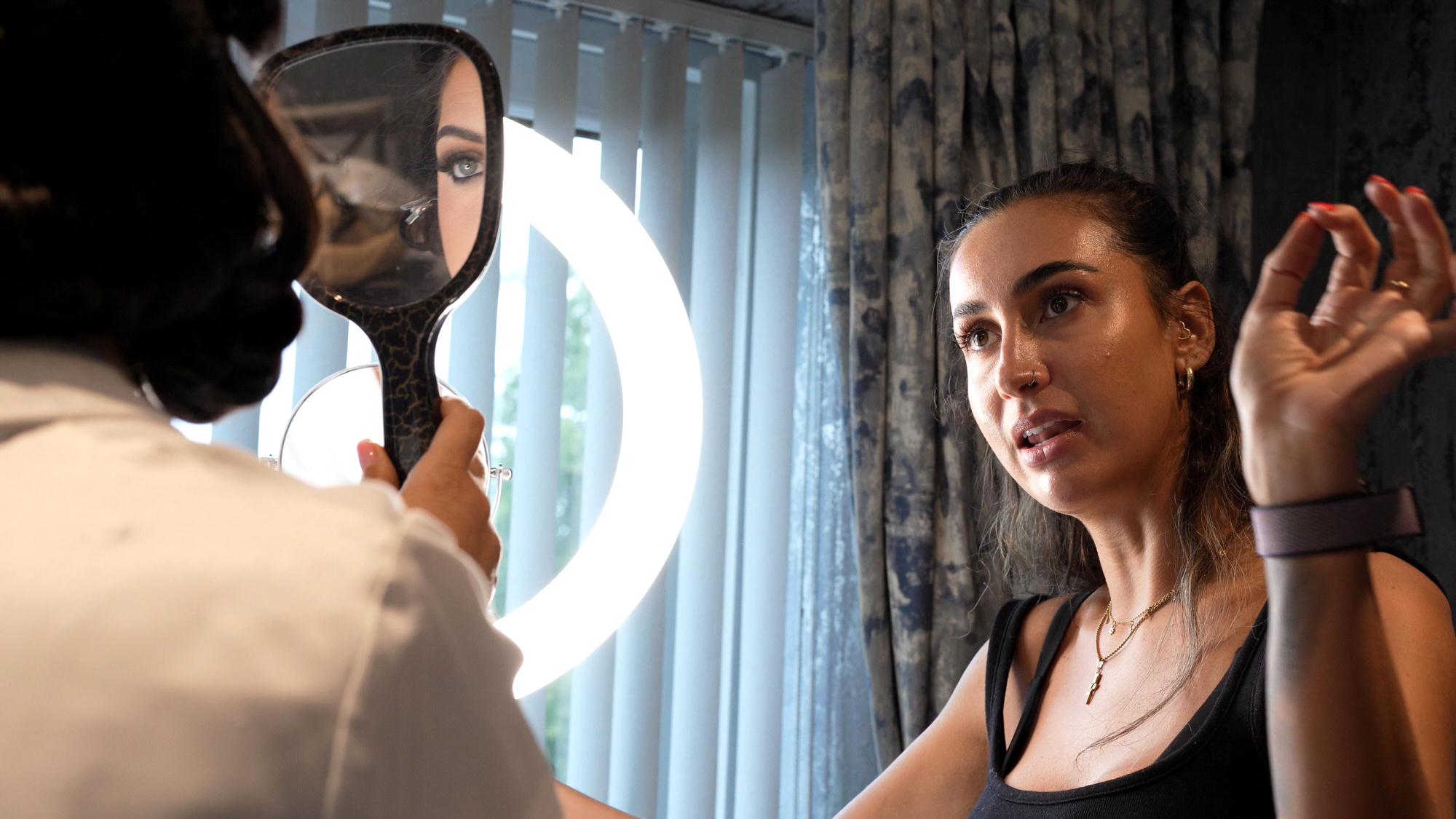 a make up artist shows the bride her finished make up
