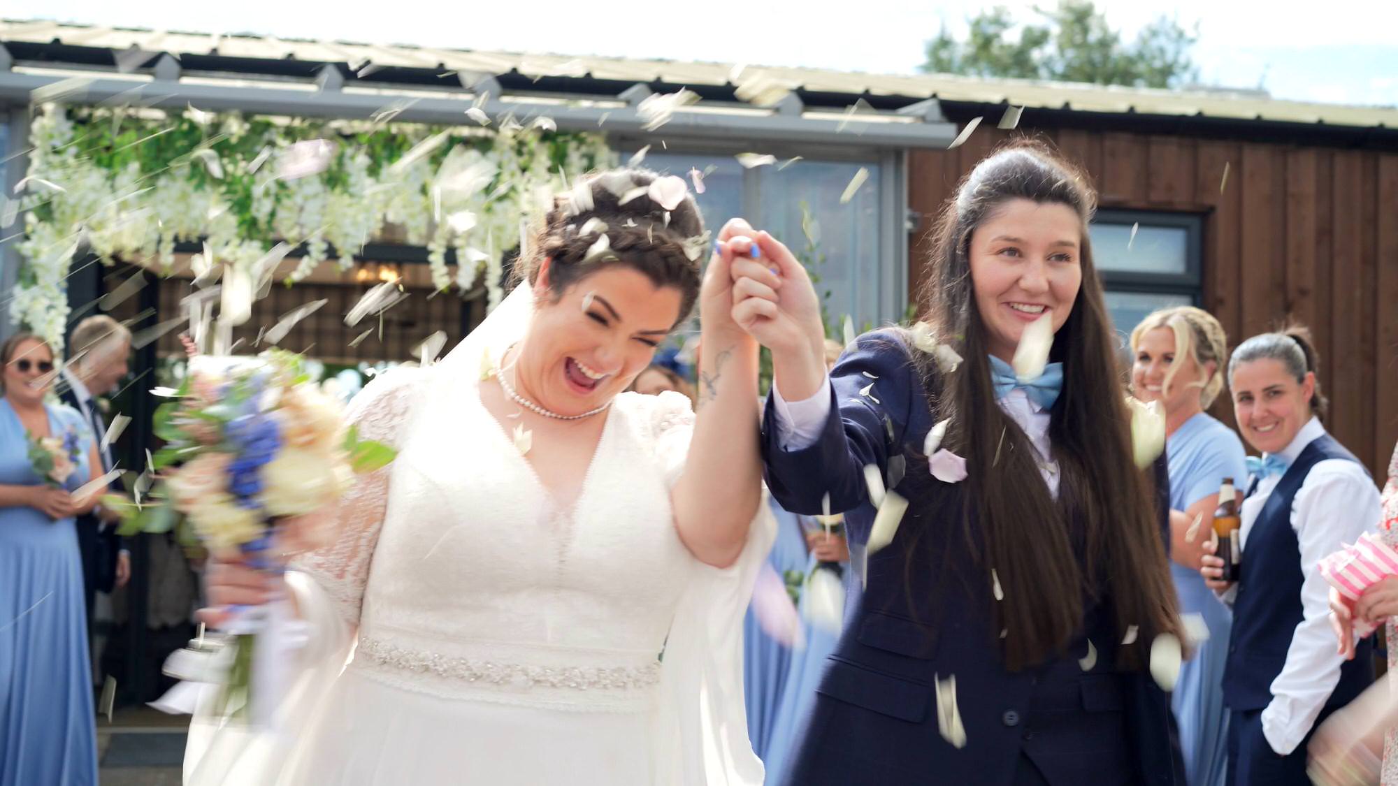 the couple laugh as they're covered in confetti outside the Aviary