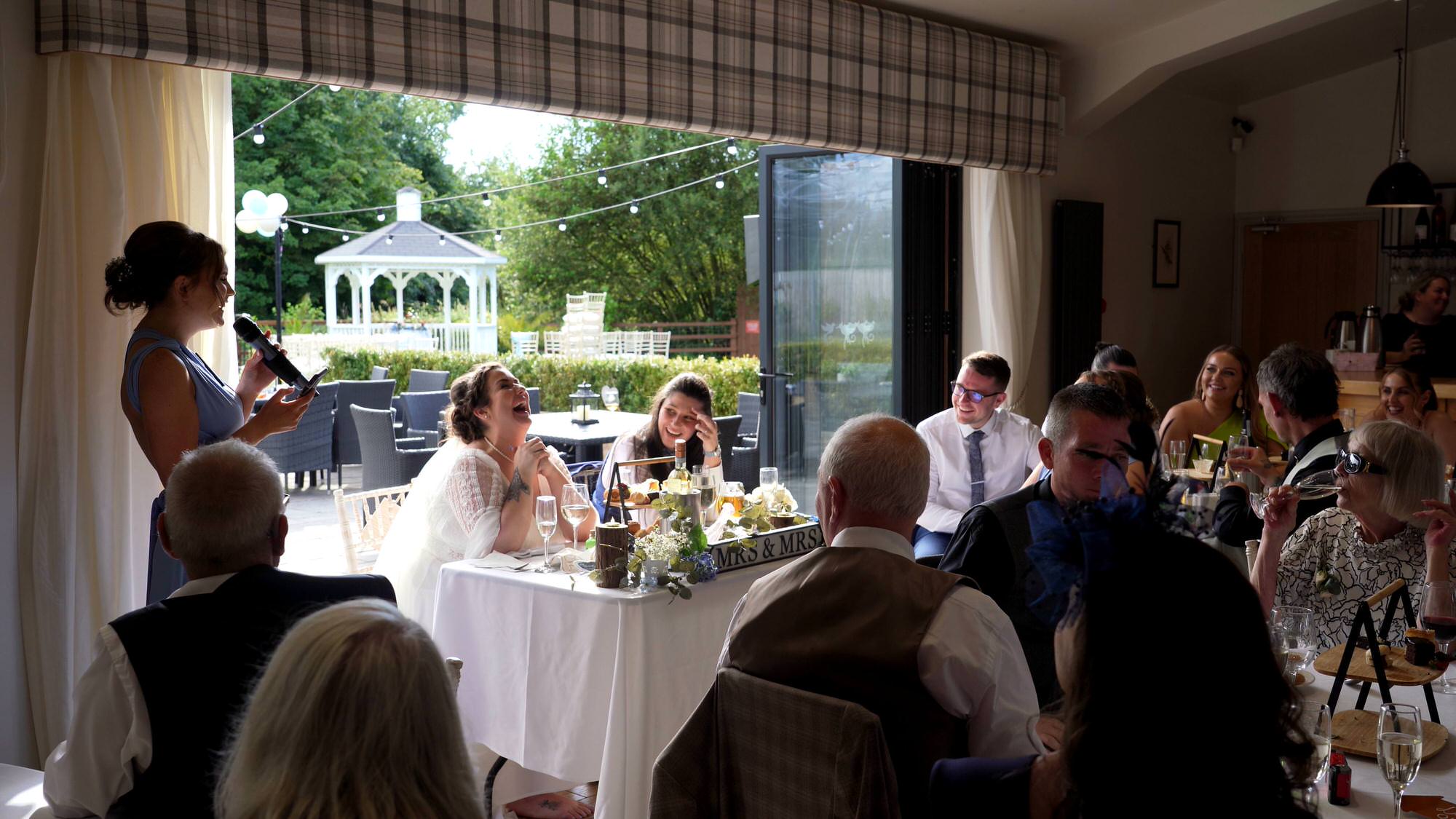 brides and guests laugh out load at a bridesmaids speech