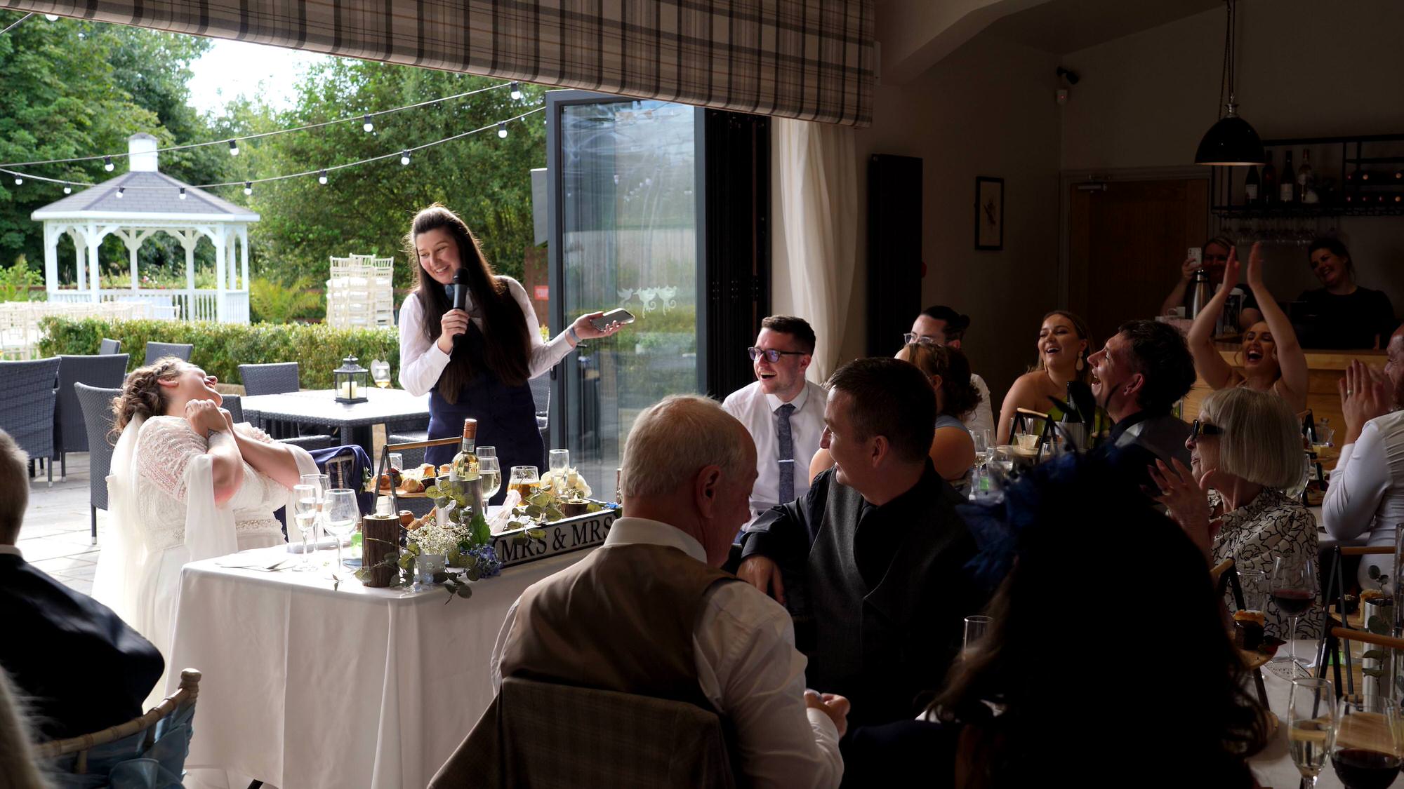 guests laugh with the brides during wedding speeches