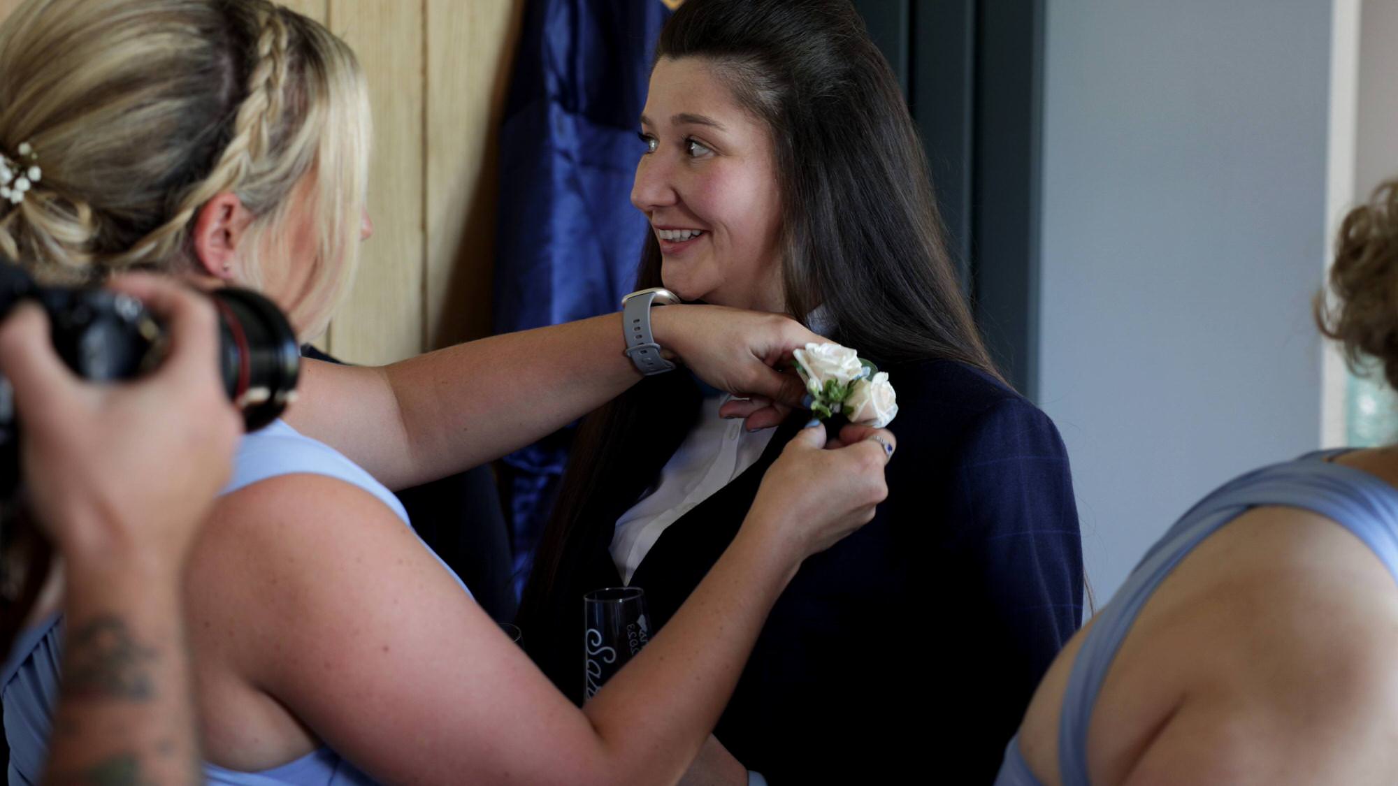 a bride gets a buttonhole pinned to her navy suit
