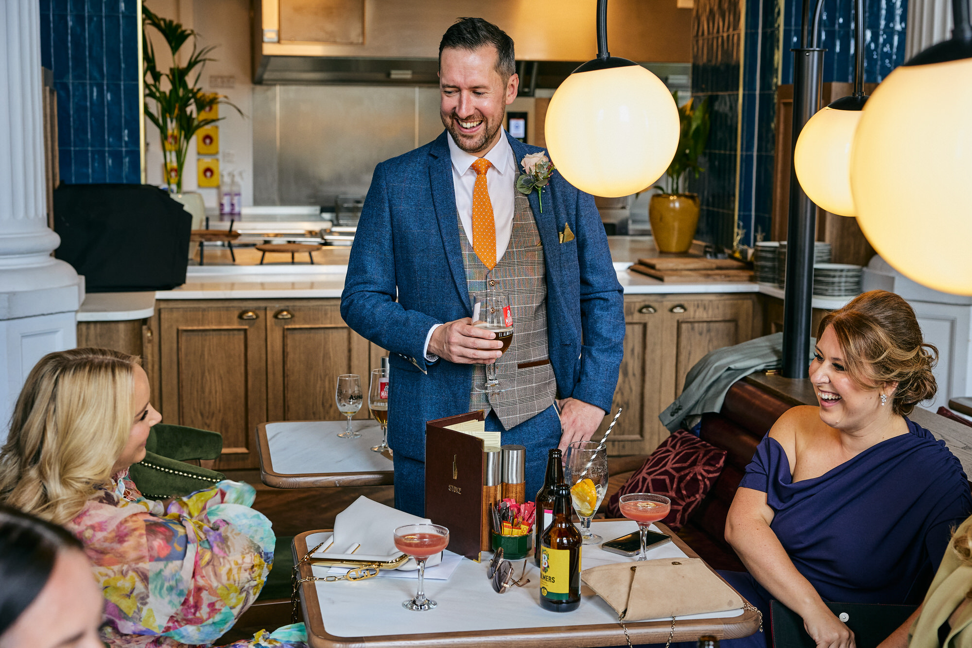 the groom laughs with wedding guests at the Radisson bar before wedding