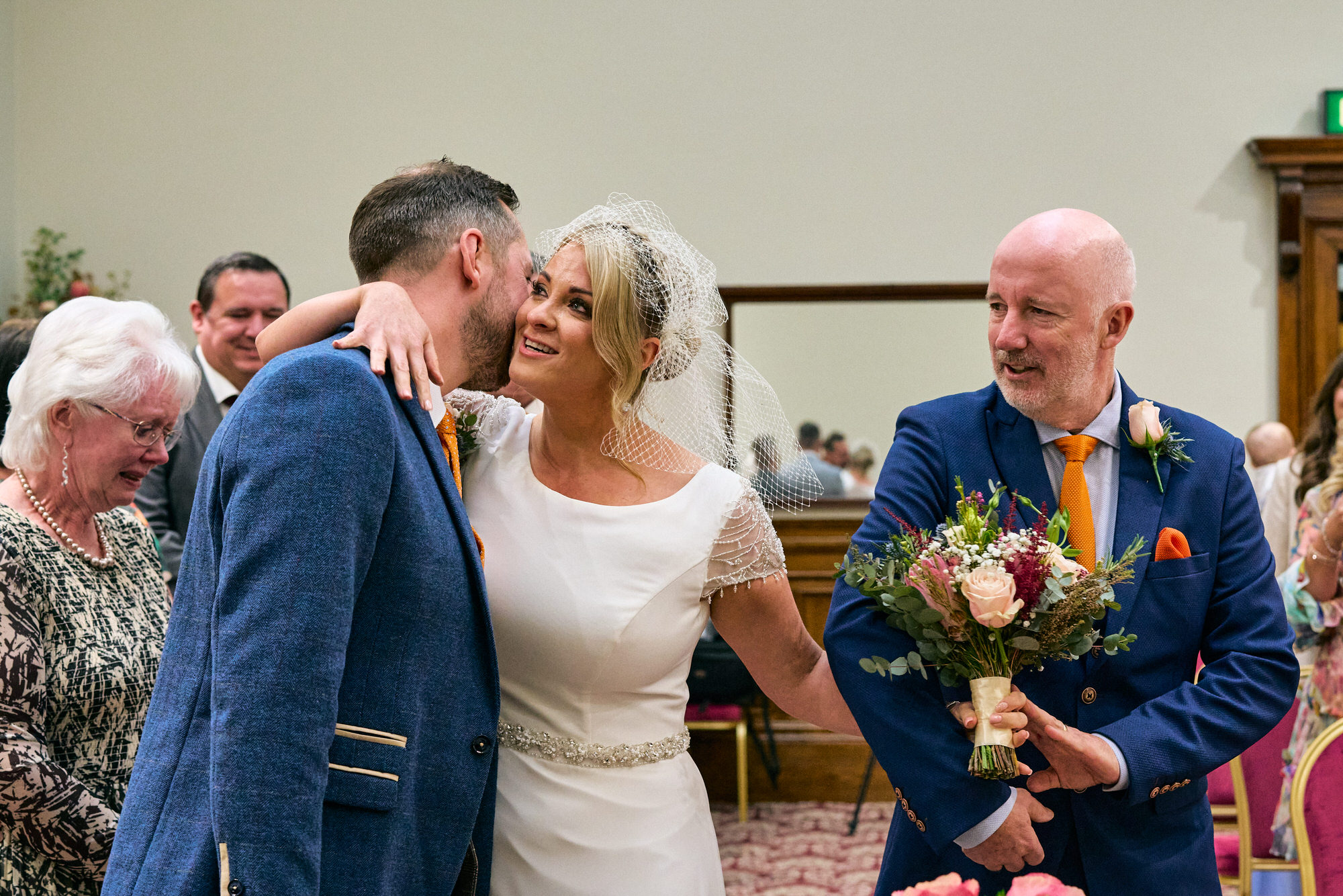 bride leans in for a kiss on the cheek during the wedding ceremony