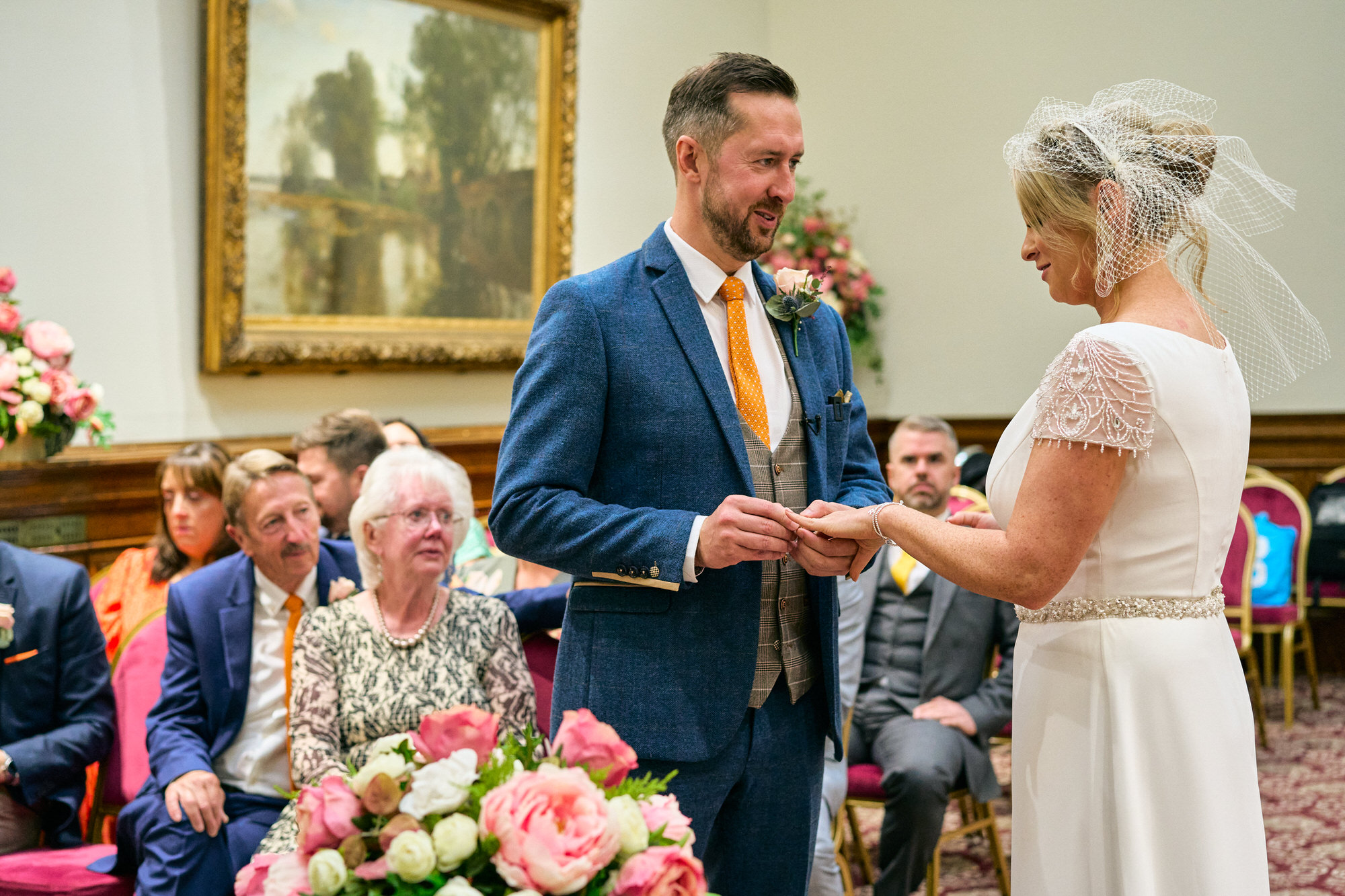the groom places the wedding ring on the bride