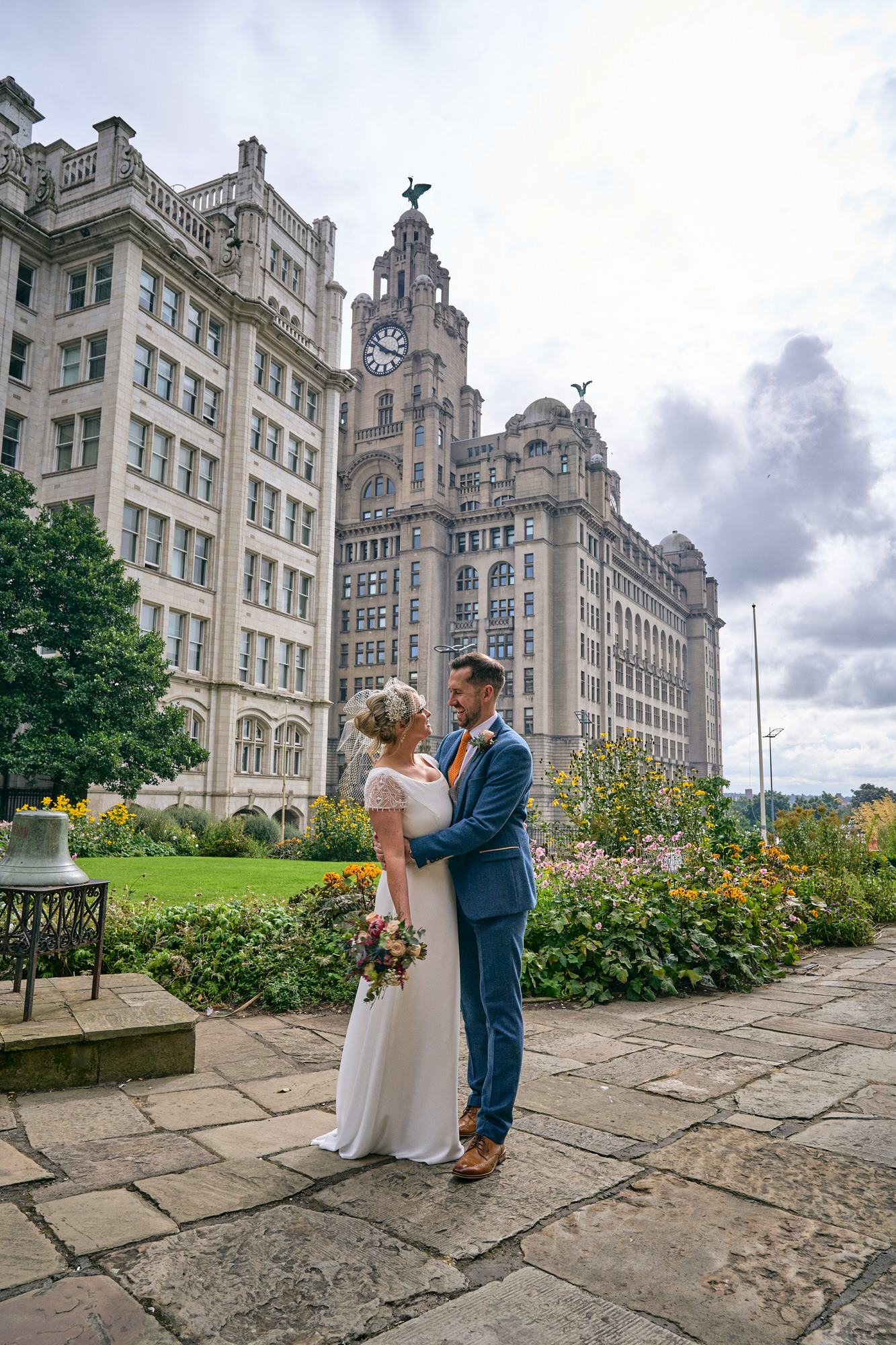 a wedding couple relax for photos in front of the Liver Building