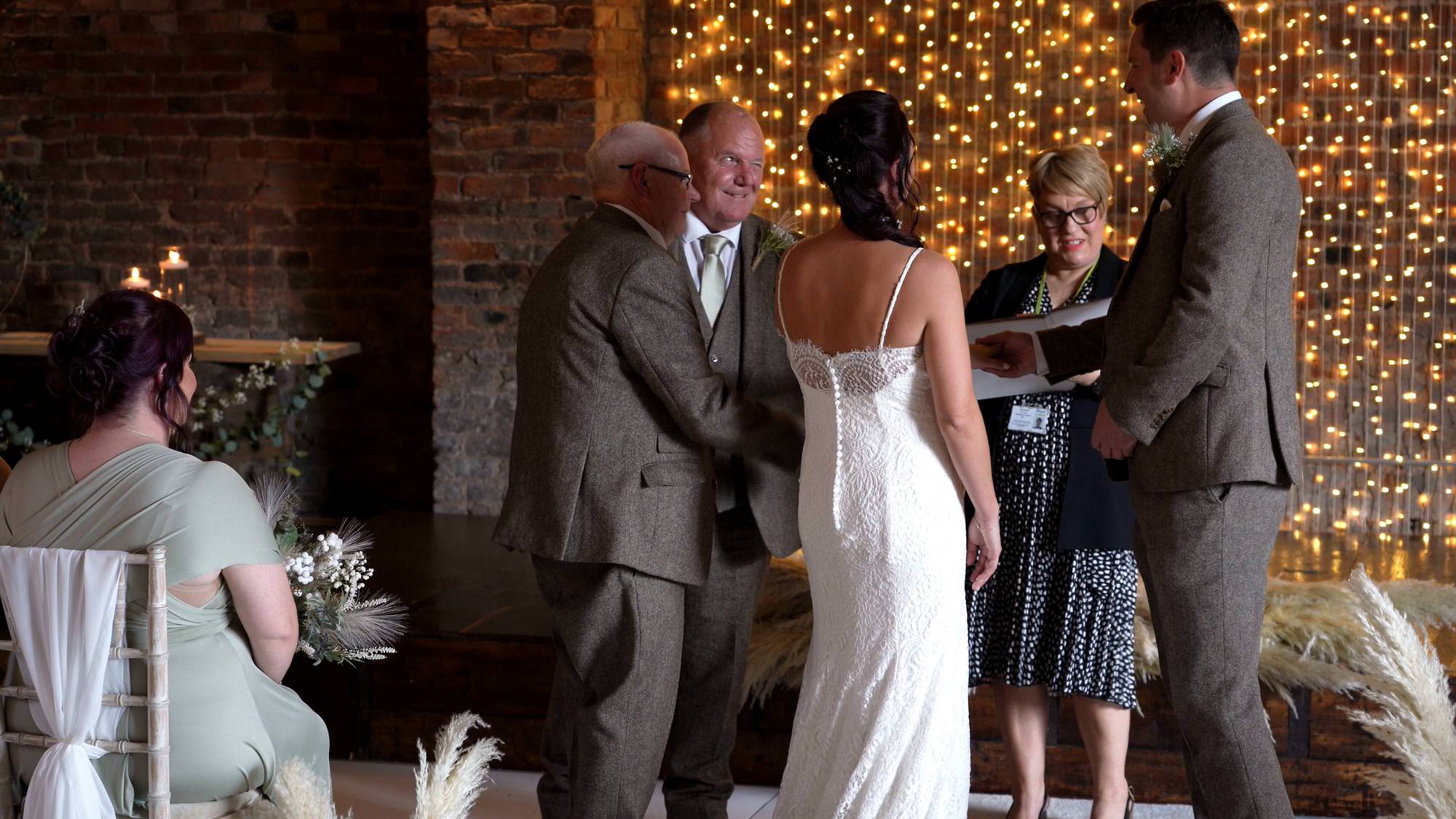 dad and grandad hand over the bride in a tradition during the ceremony