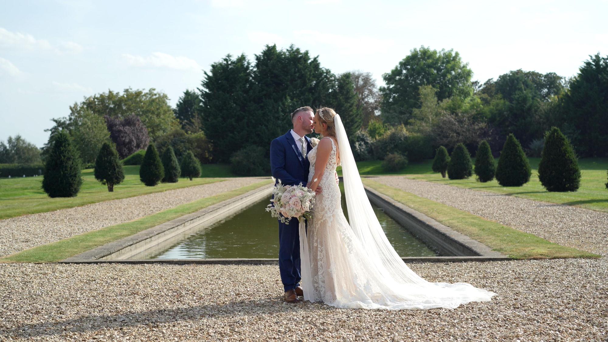a bride and groom pose by the pond and fountain outside Stubton Hall Newark