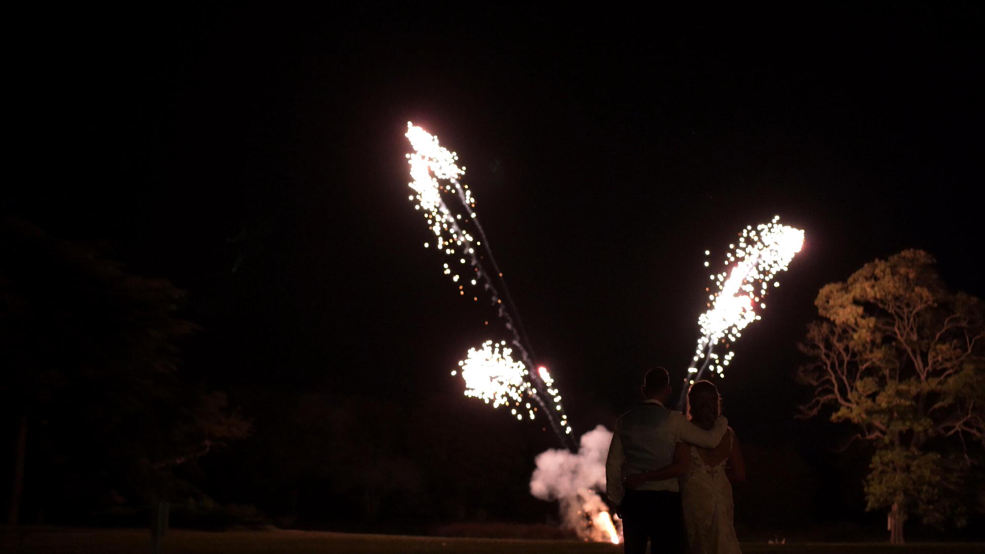 a couple stand on the grounds of Stubton Hall to watch fireworkds