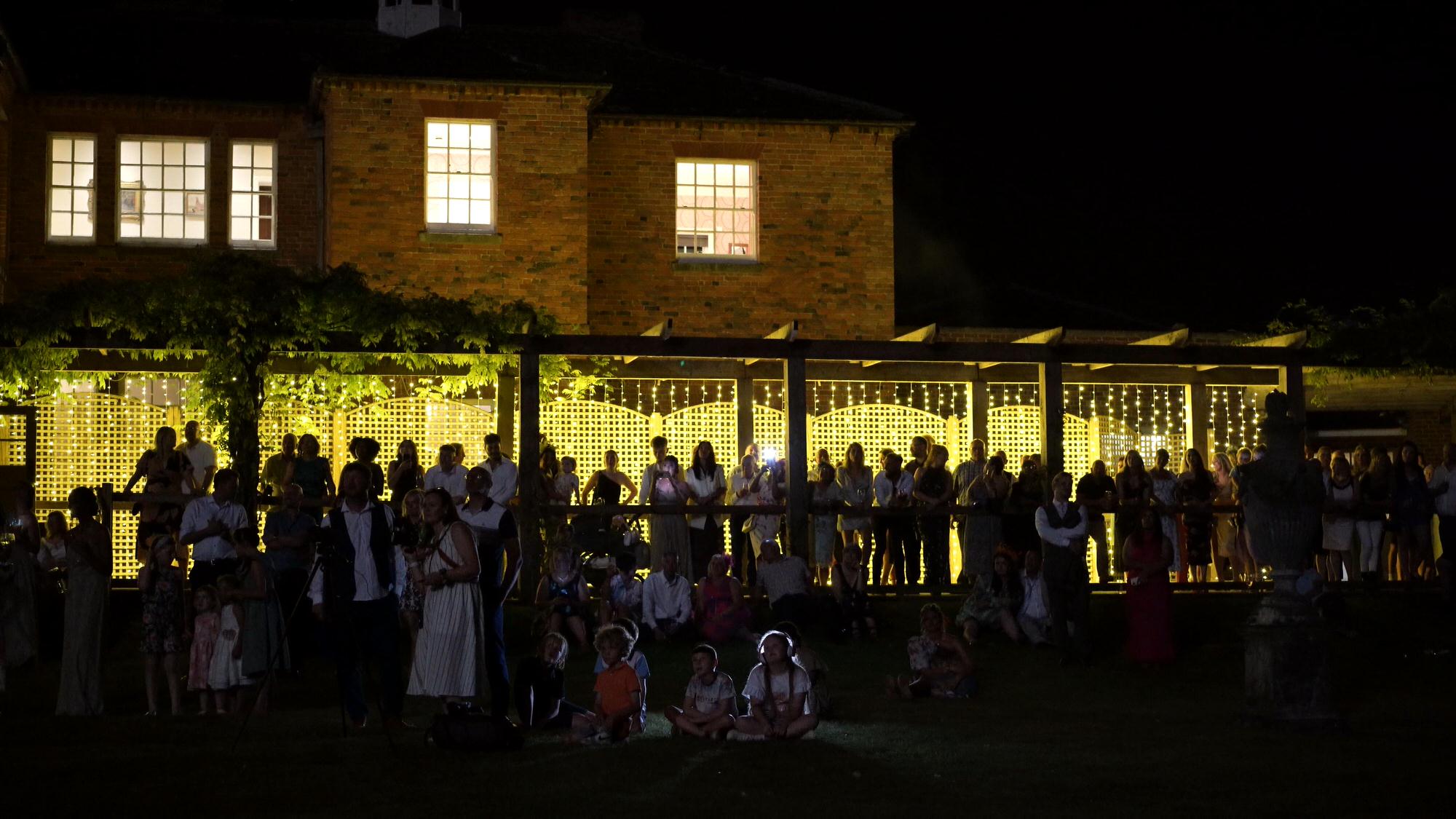 a video still of guests on the terrace watching fireworks
