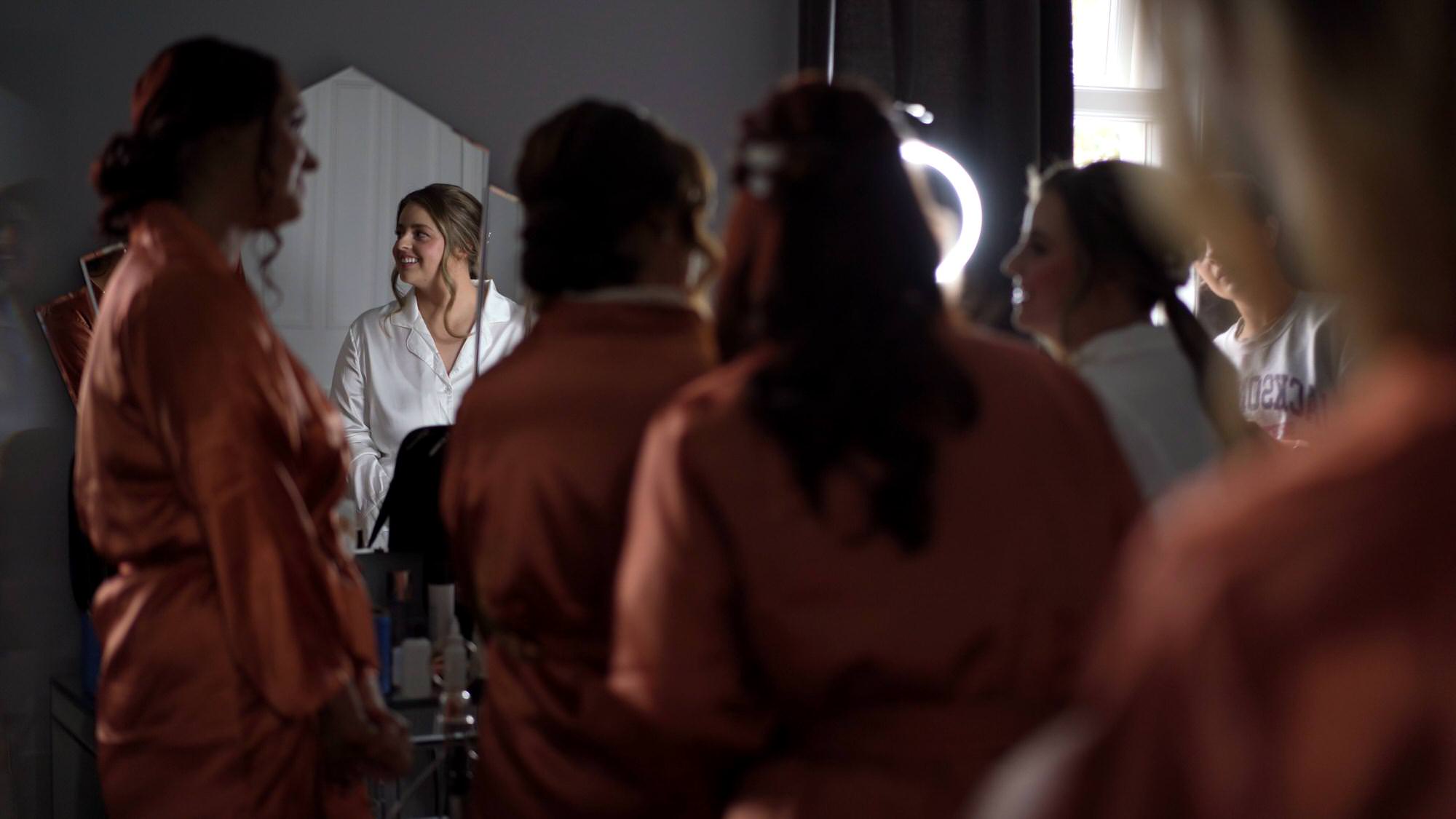 bridemaids gather around the bride to see her makeup at Cartmel Old Grammar