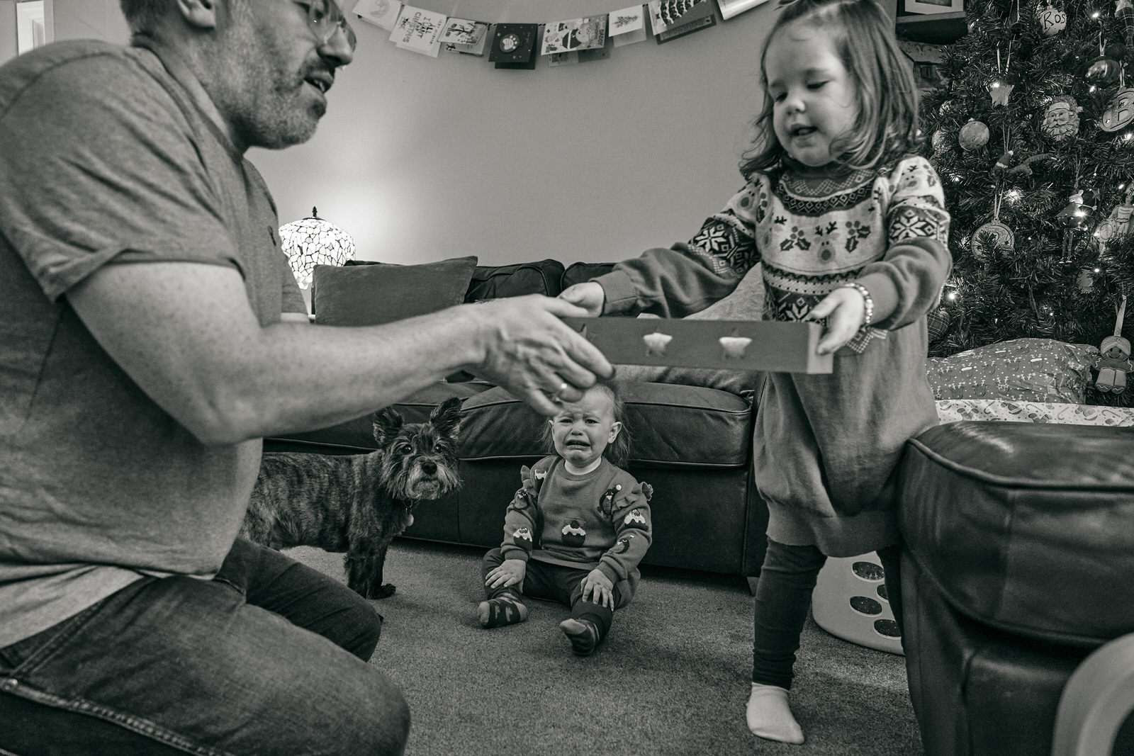 a baby cries as her sister helps with the christmas even boxes for Santa