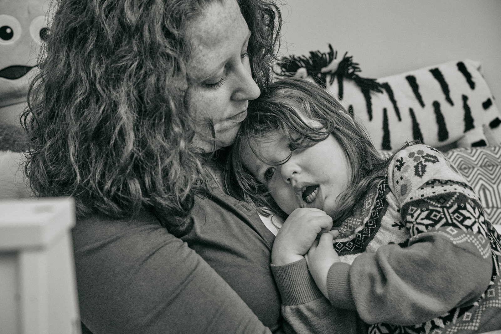 a little girl in a christmas jumper cuddles her mum
