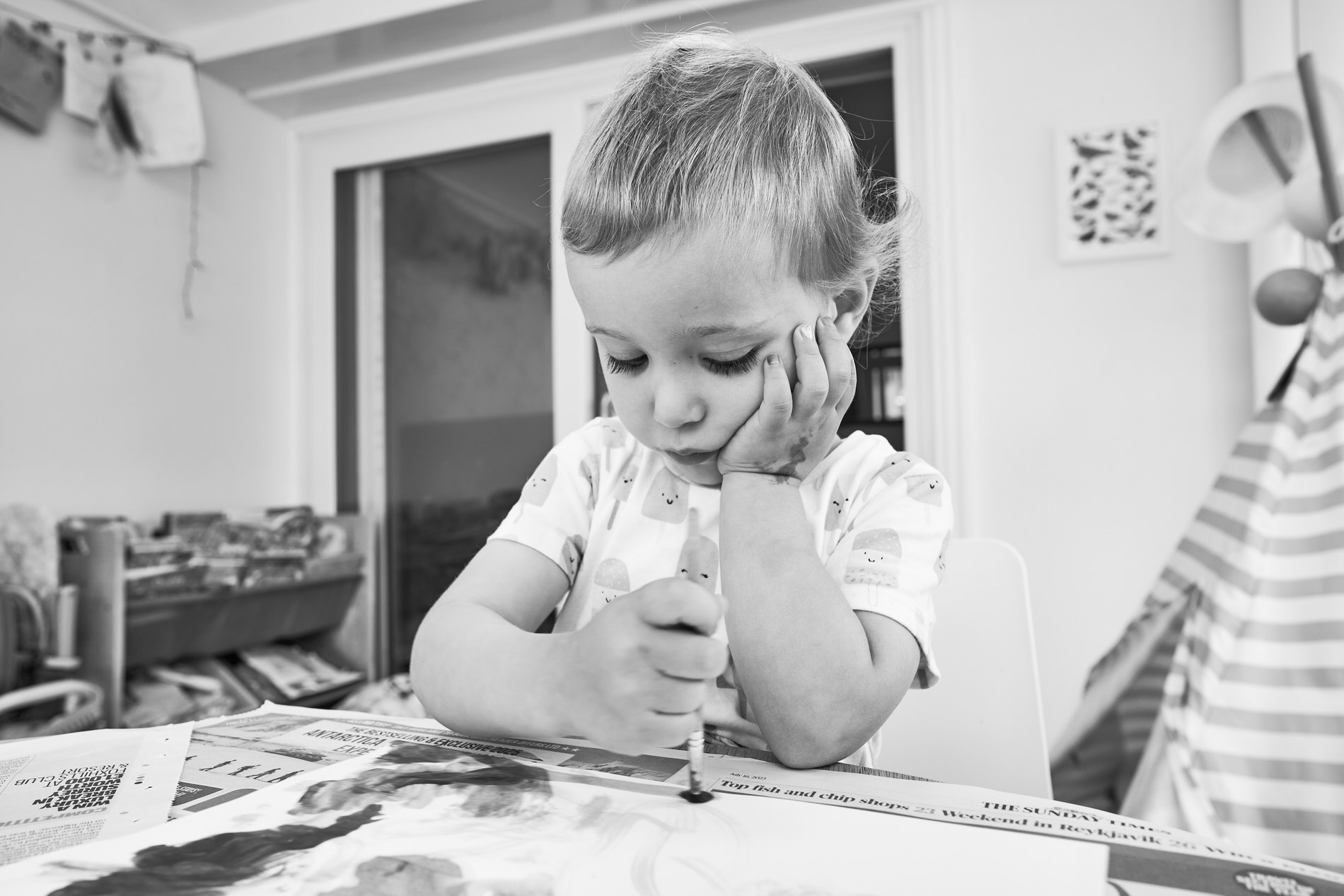 a little girl leans on her hand whilst crafting at home