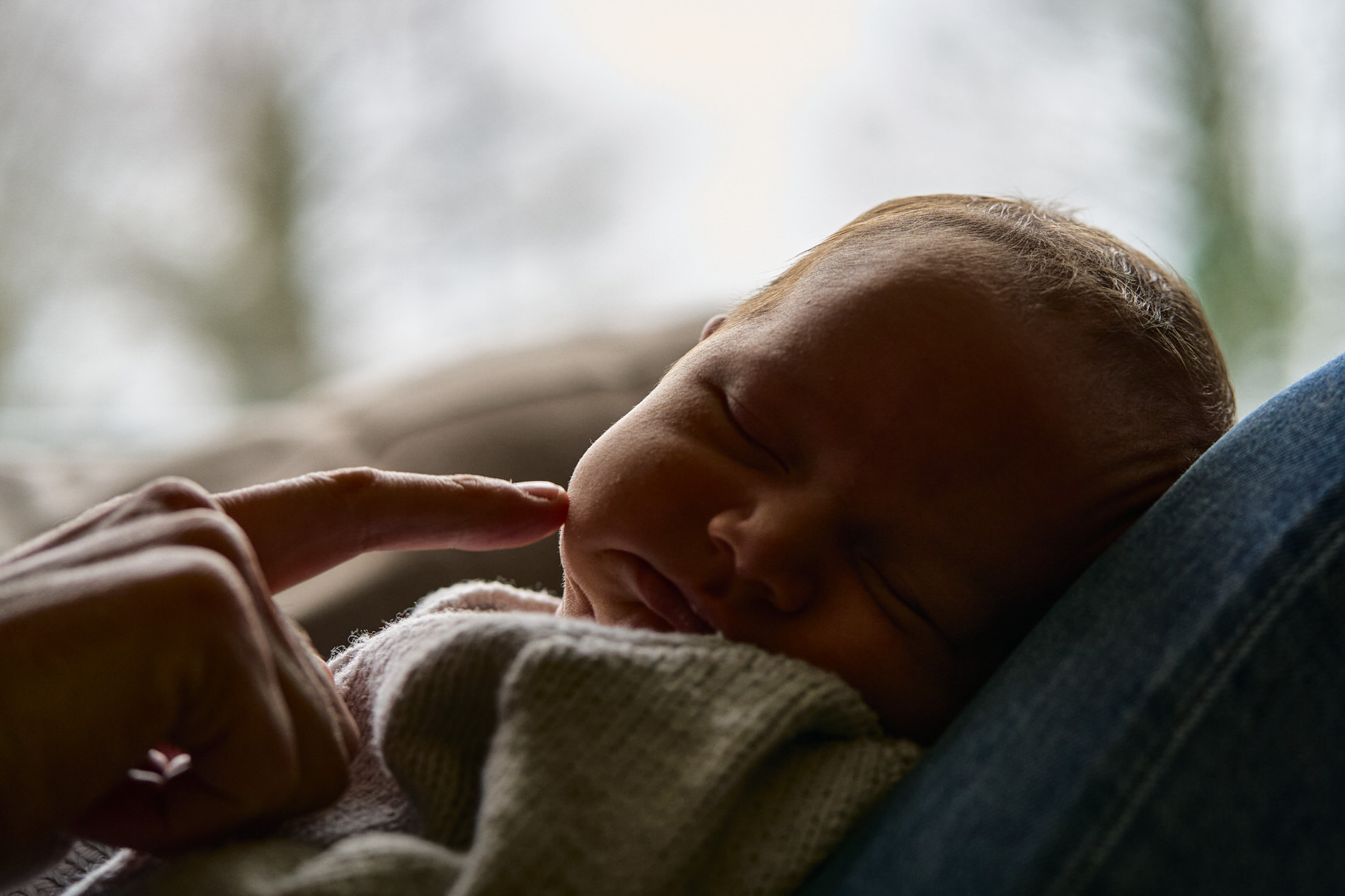 a dad gently touches his babys squishy cheeks