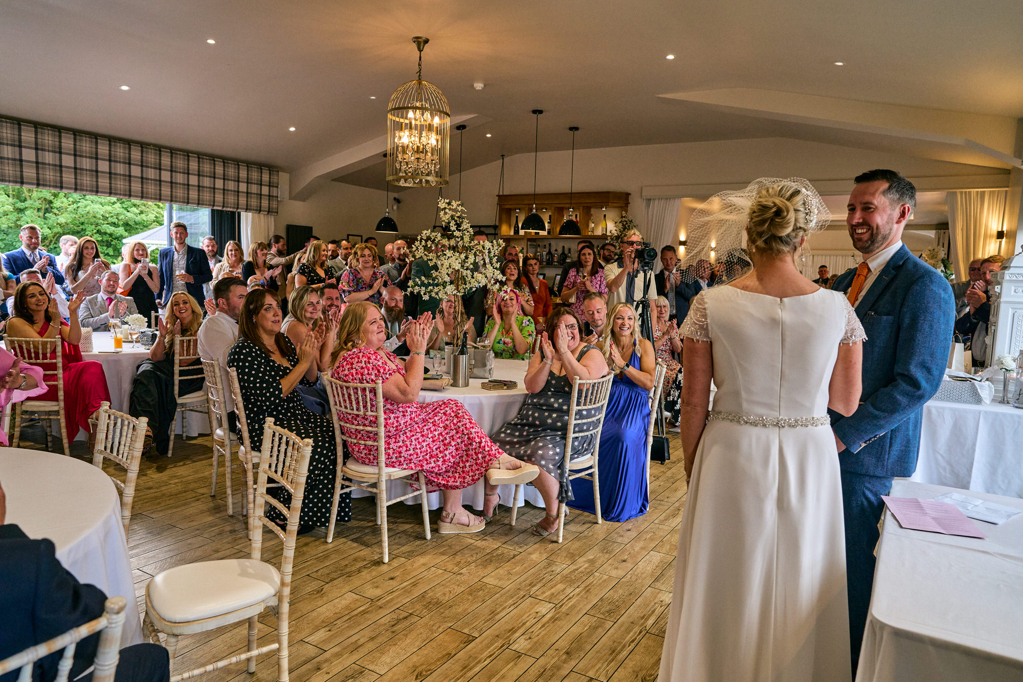 a wide room photo of all the guests cheering for the couple
