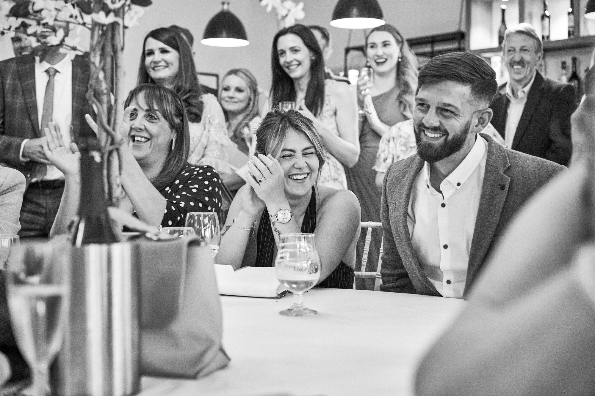 a guests hides her face as she laughs during the wedding speeches