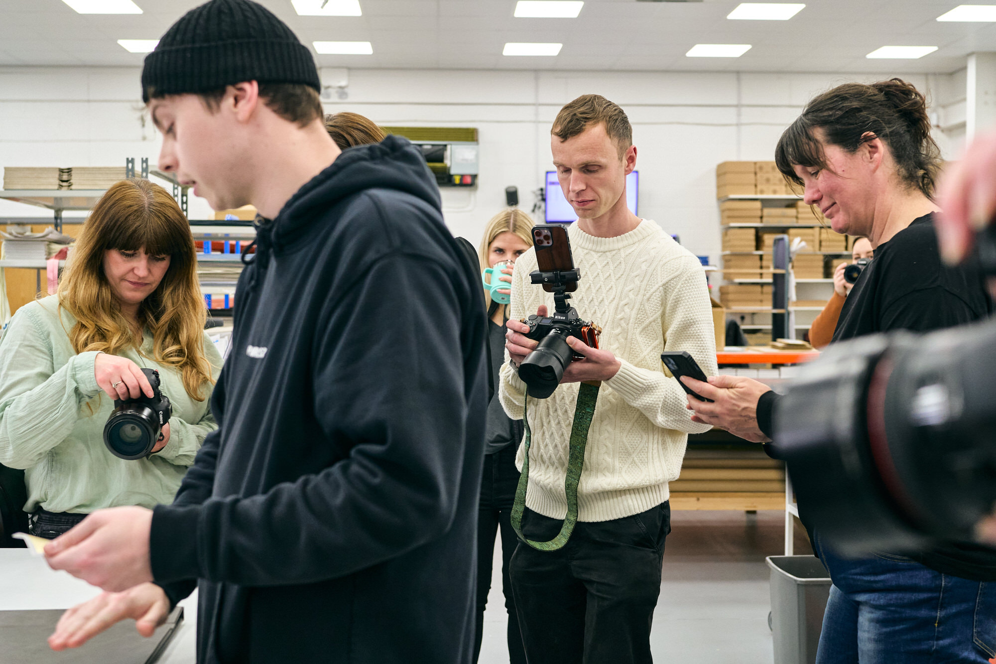 photographers gather around to watch someone add gold foiling to an album