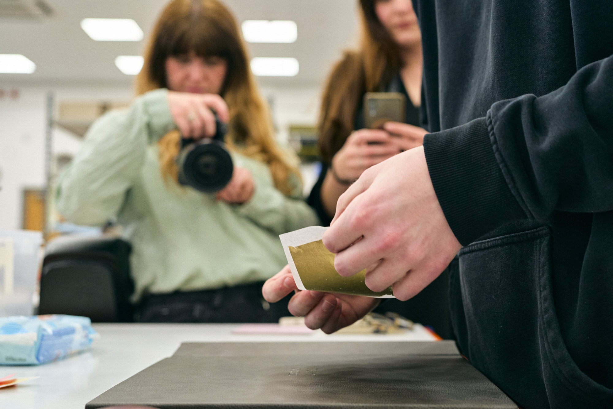 a close up photo of hands working with gold foiling on a wedding album