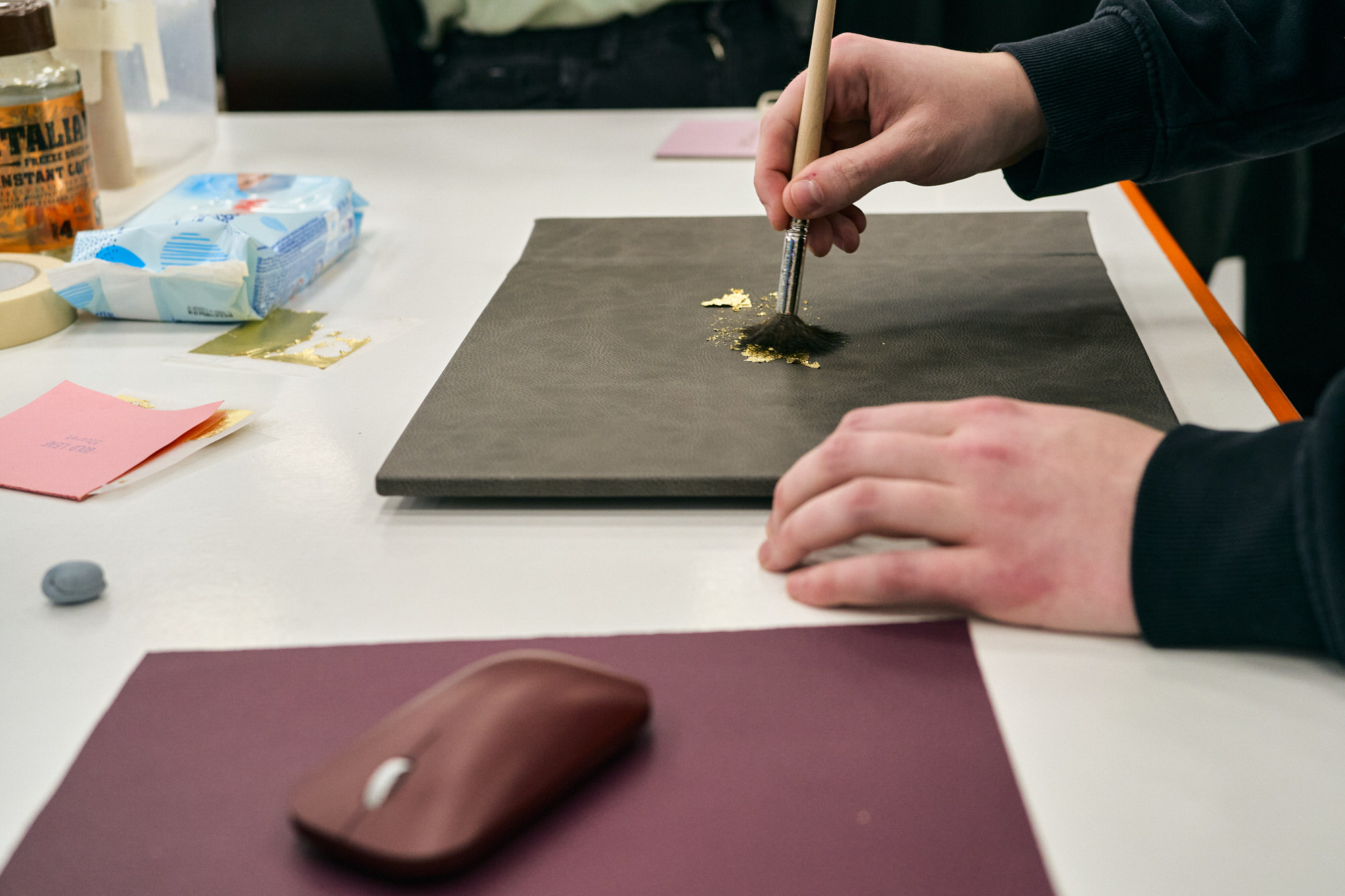 someone gently brushes off gold foil on a wedding album cover