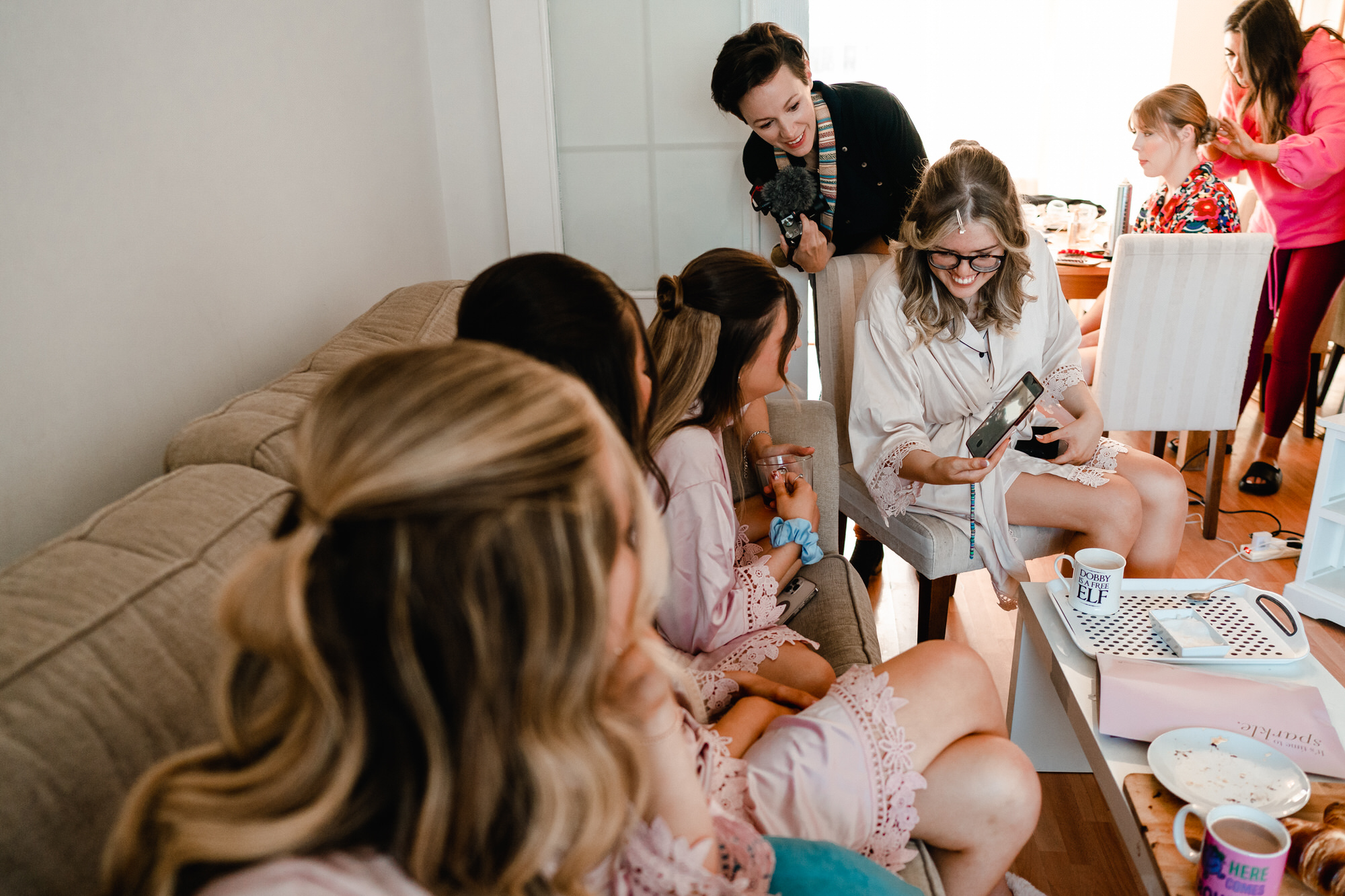 videographer laughs with bride looking at content on her phone