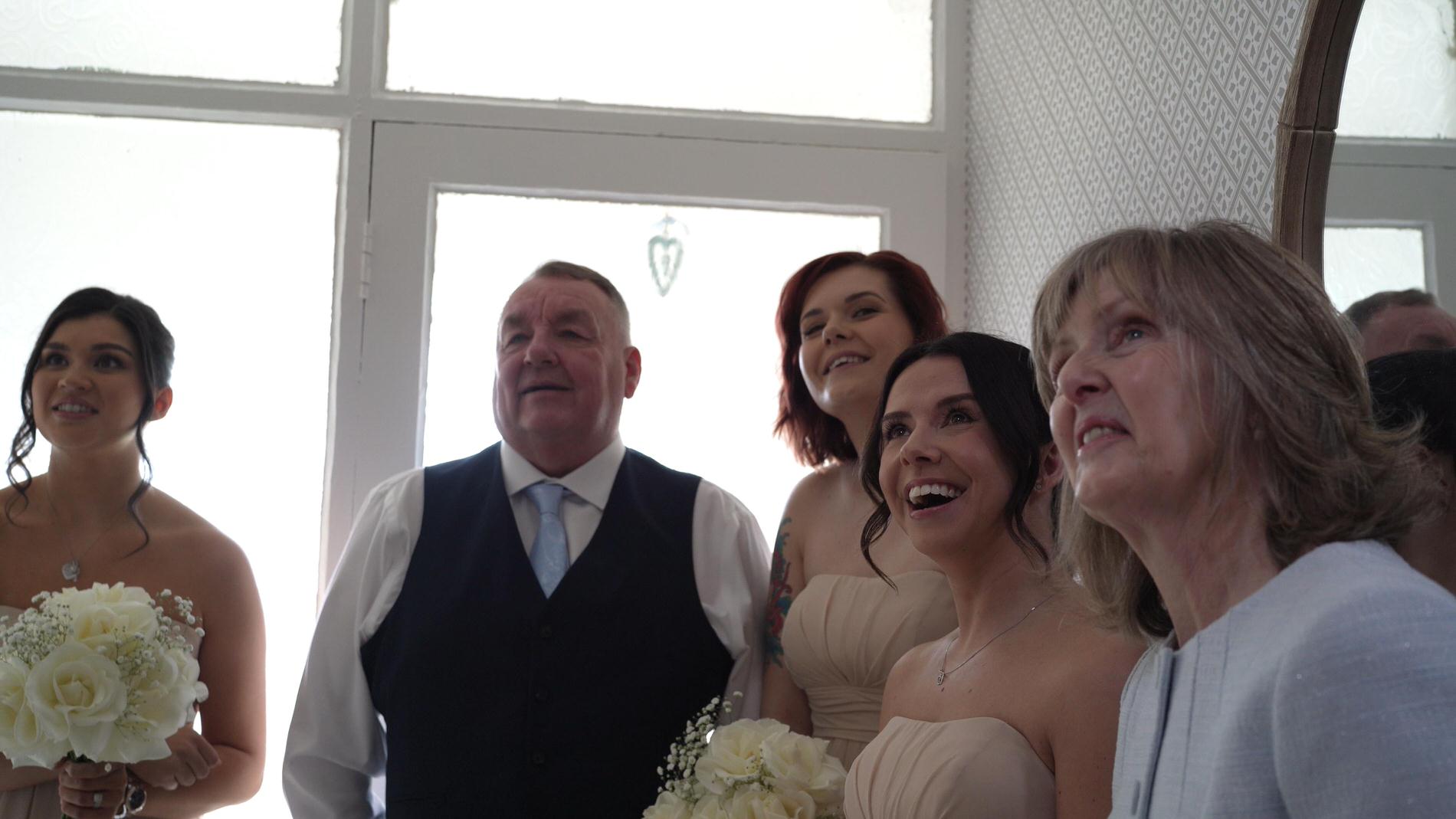 a video still of the reaction of her bridesmaids and parents to the bride