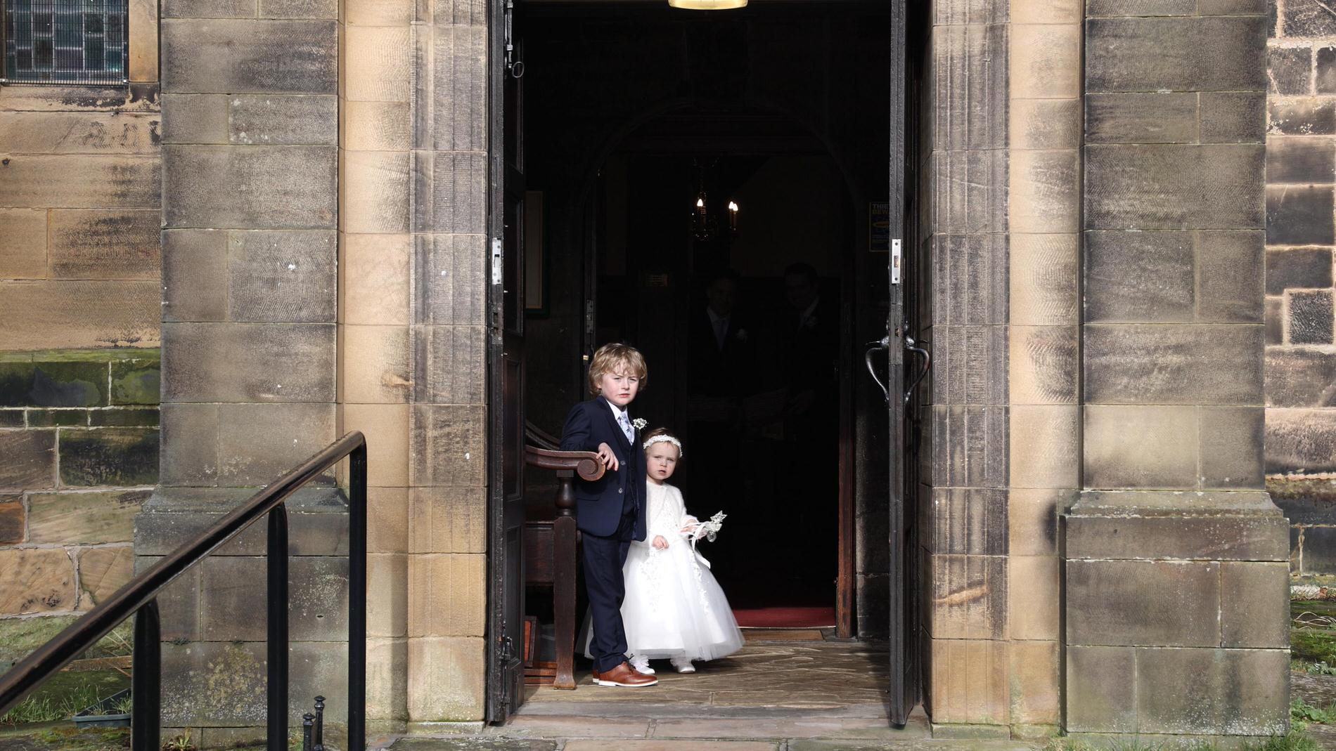 a candid video still of a page boy and flower girl waiting in the church door