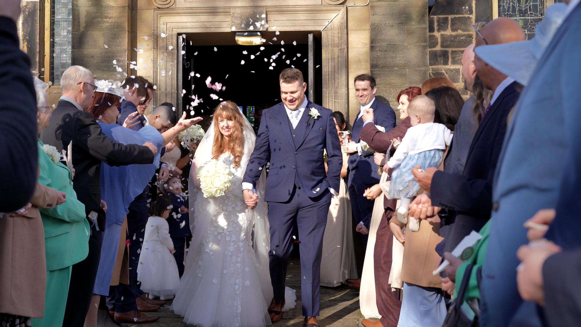 a video still of the couple enjoying their wedding confetti shot outside St Cuthberts Church in Churchtown