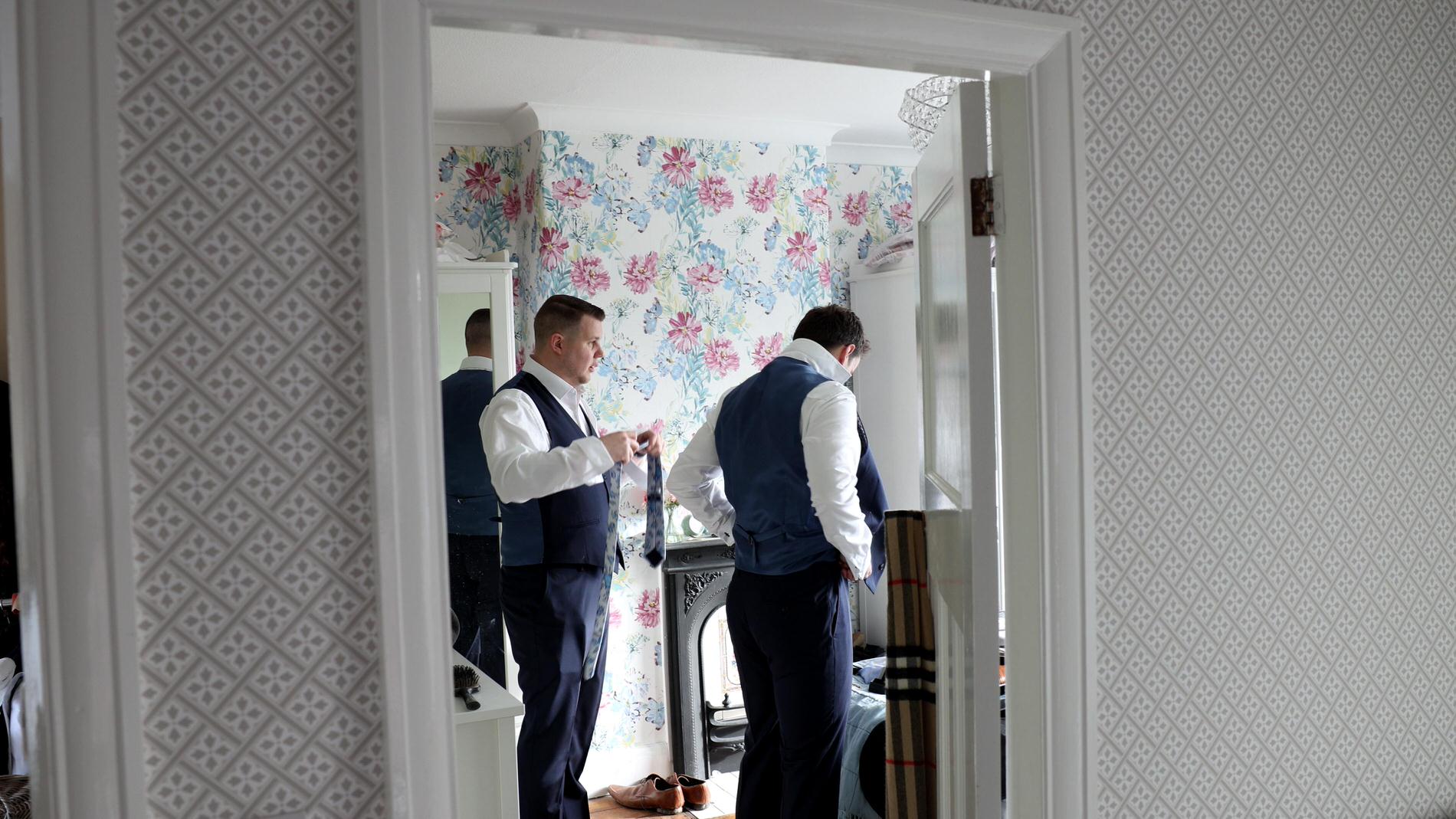 a groom gets ready at home with his groomsmen