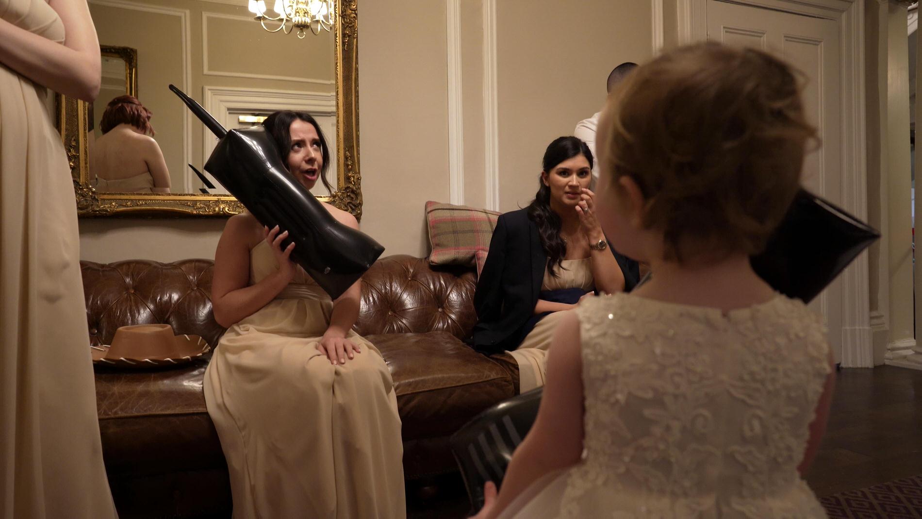 a bridemaid and flower girl play with photobooth props