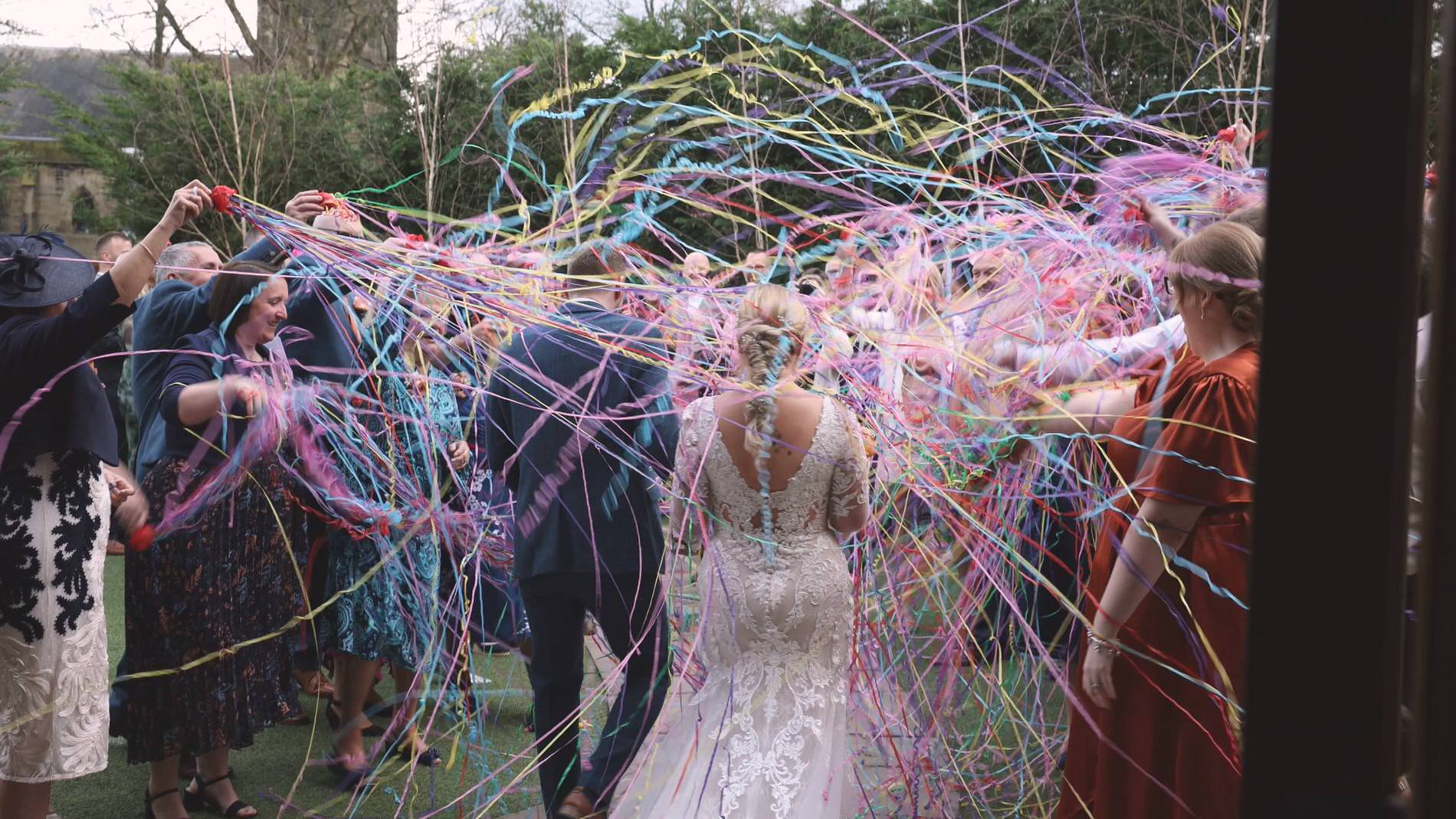 a couple get covered in colourful wedding confetti streamers at Manor House Lindley