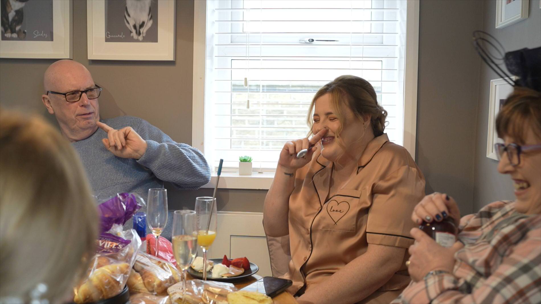 a bridesmaid and brides parents belly laugh during the wedding morning