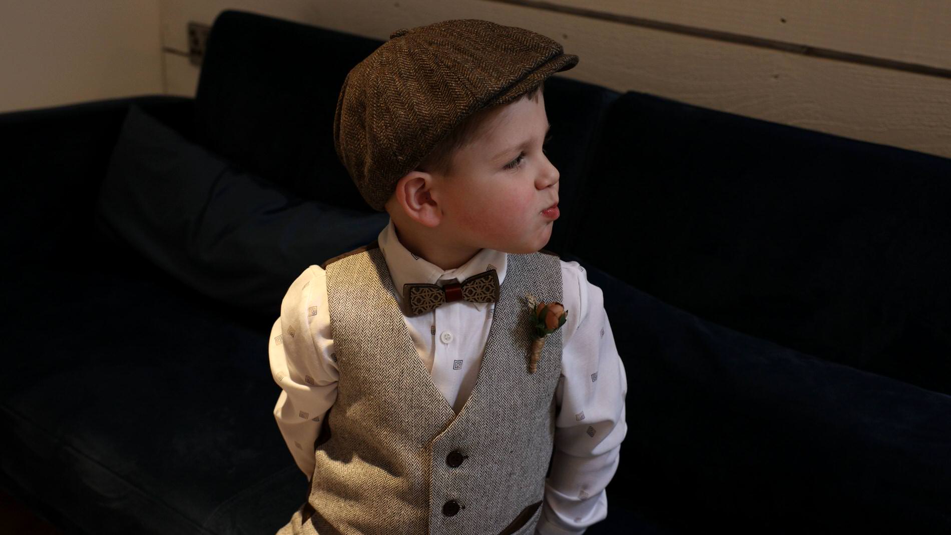a little page boy dressed in a waistcoat and flatcap