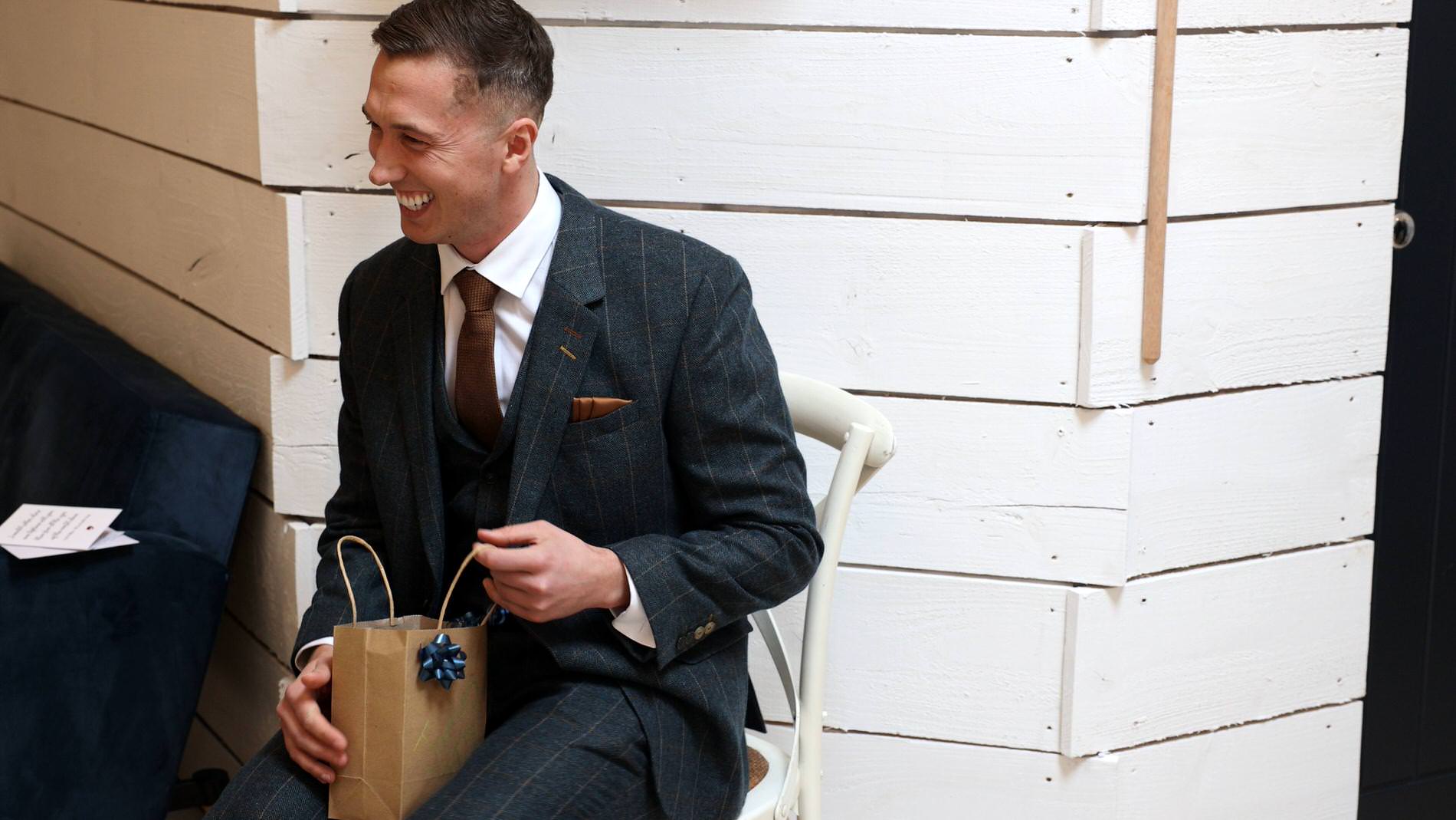 the groom laughs as he opens his wedding gift