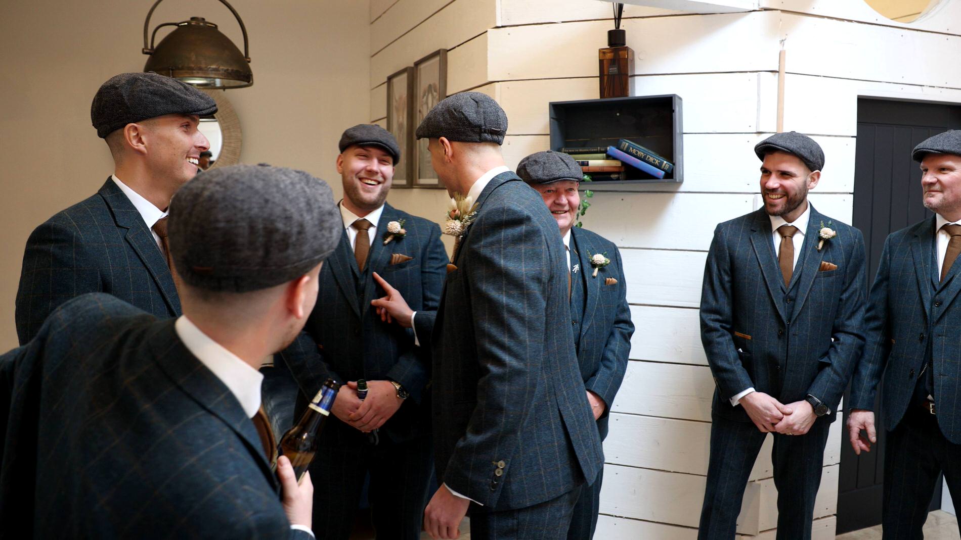 the groom laughs with his groomsmen pretending to be Peaky Blinders